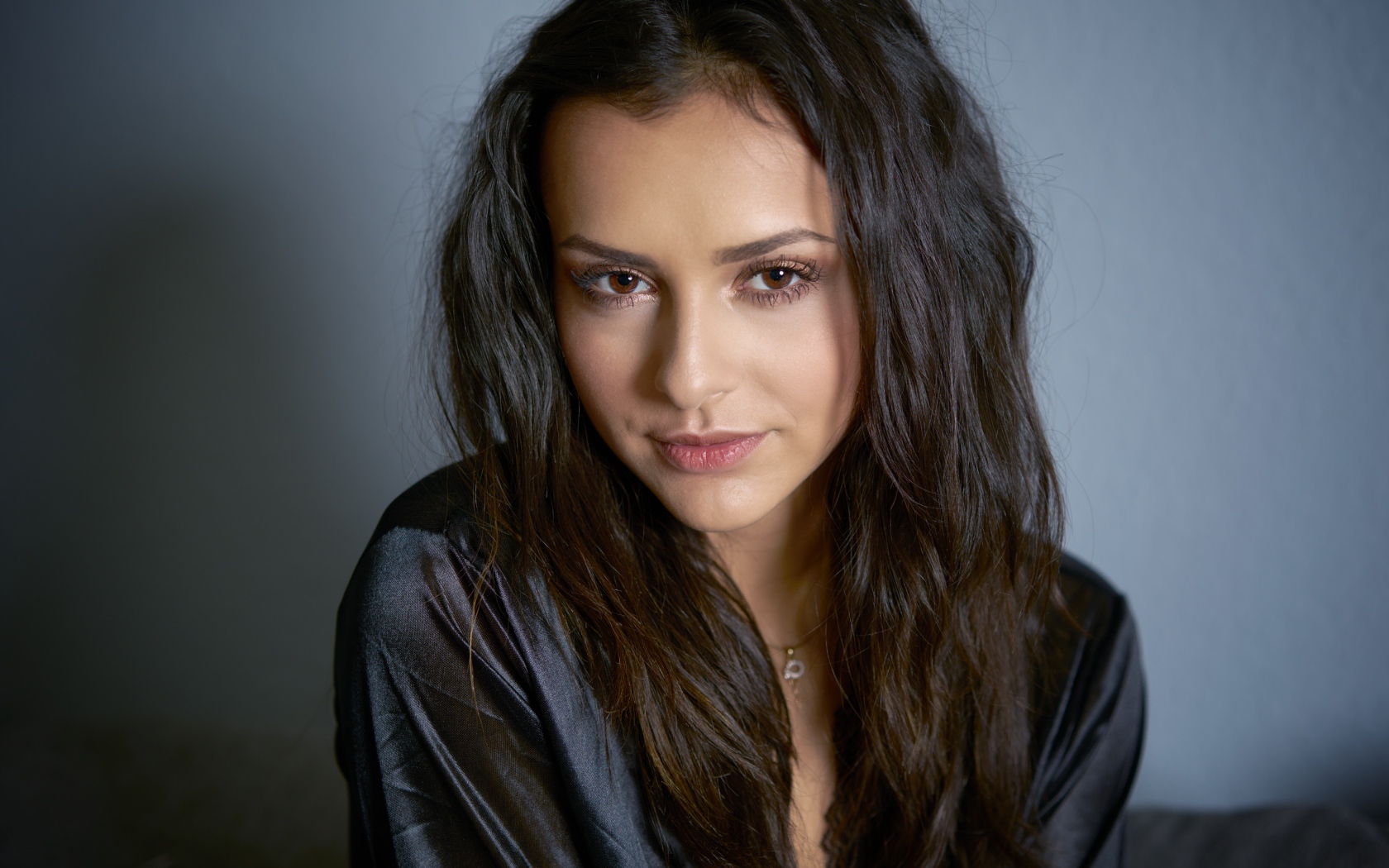 Кареглазая брюнетка в черном халате на сером фоне