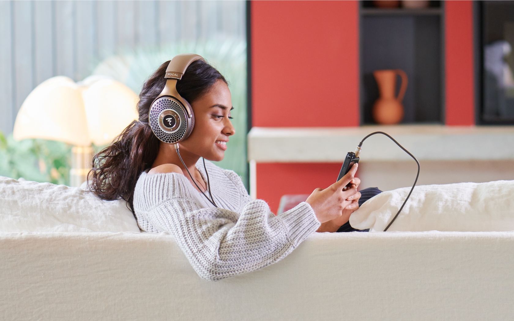 Девушка модель в наушниках на диване с плеером