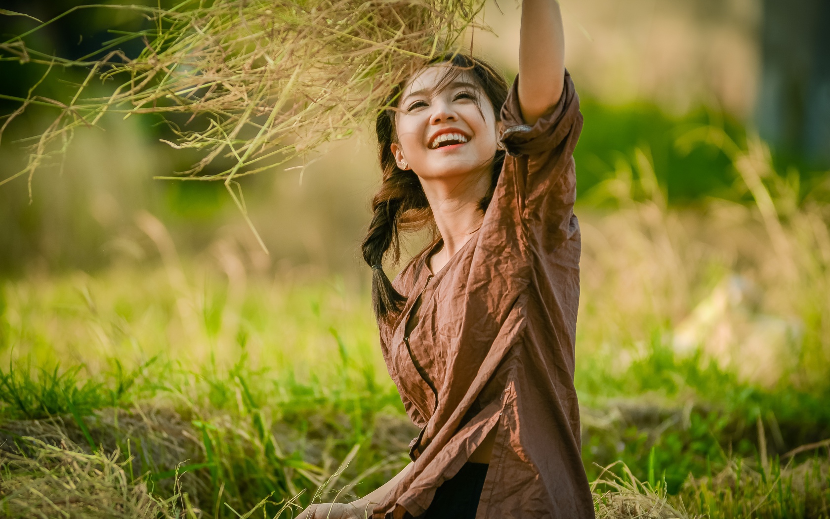 Улыбающаяся девушка азиатка с травой в руках 