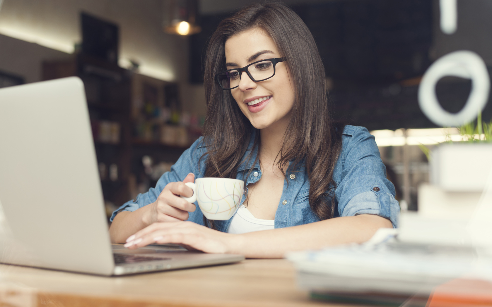 Улыбающаяся девушка в очках с ноутбуком