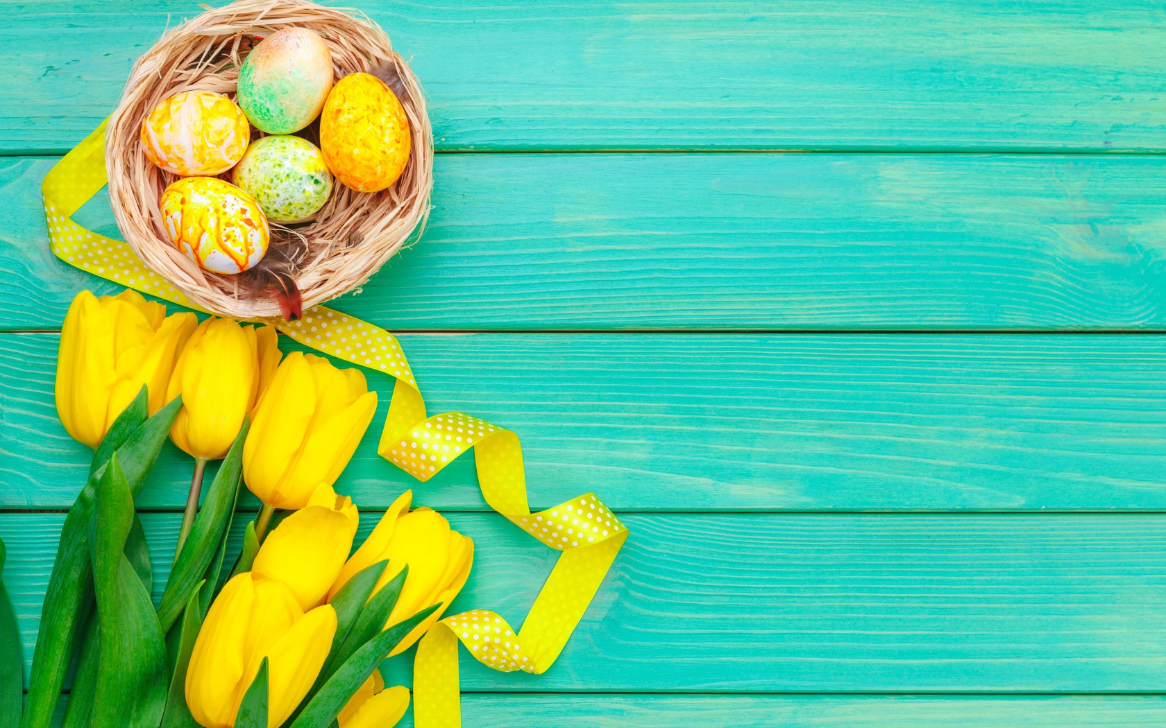 Разноцветные пасхальные яйца  и букет желтых тюльпанов на голубом фоне