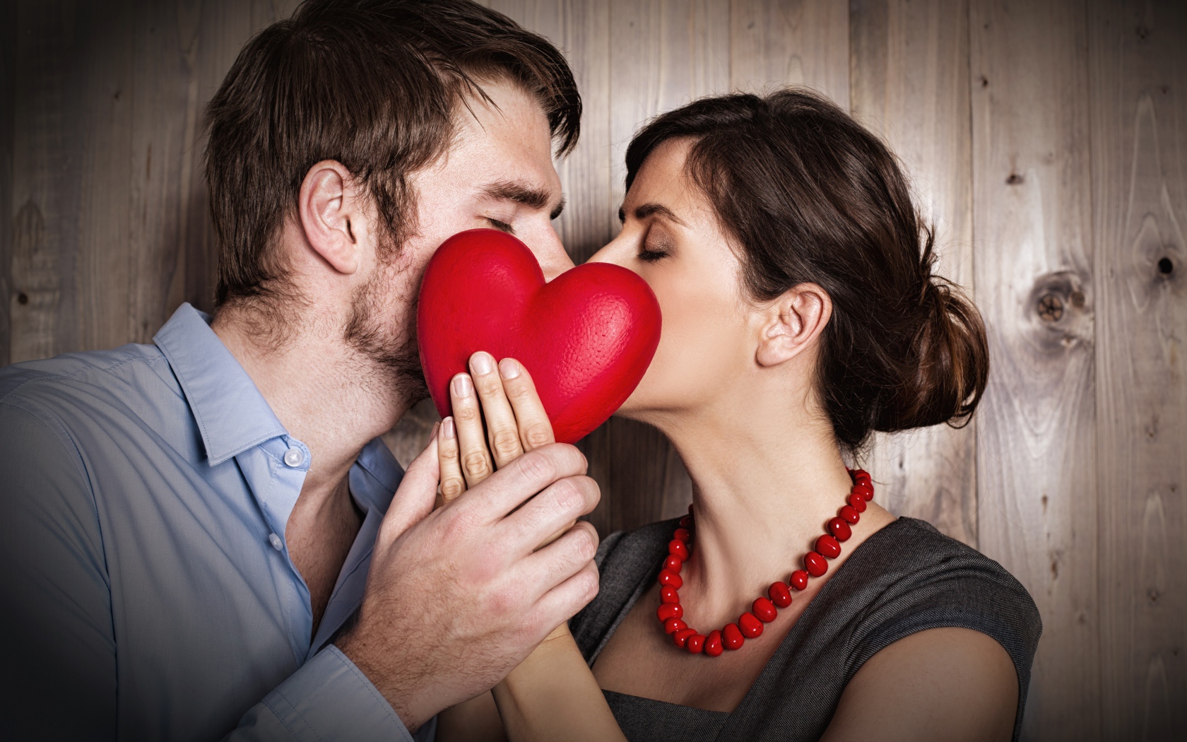 Поцелуй влюбленной пары за красным сердцем