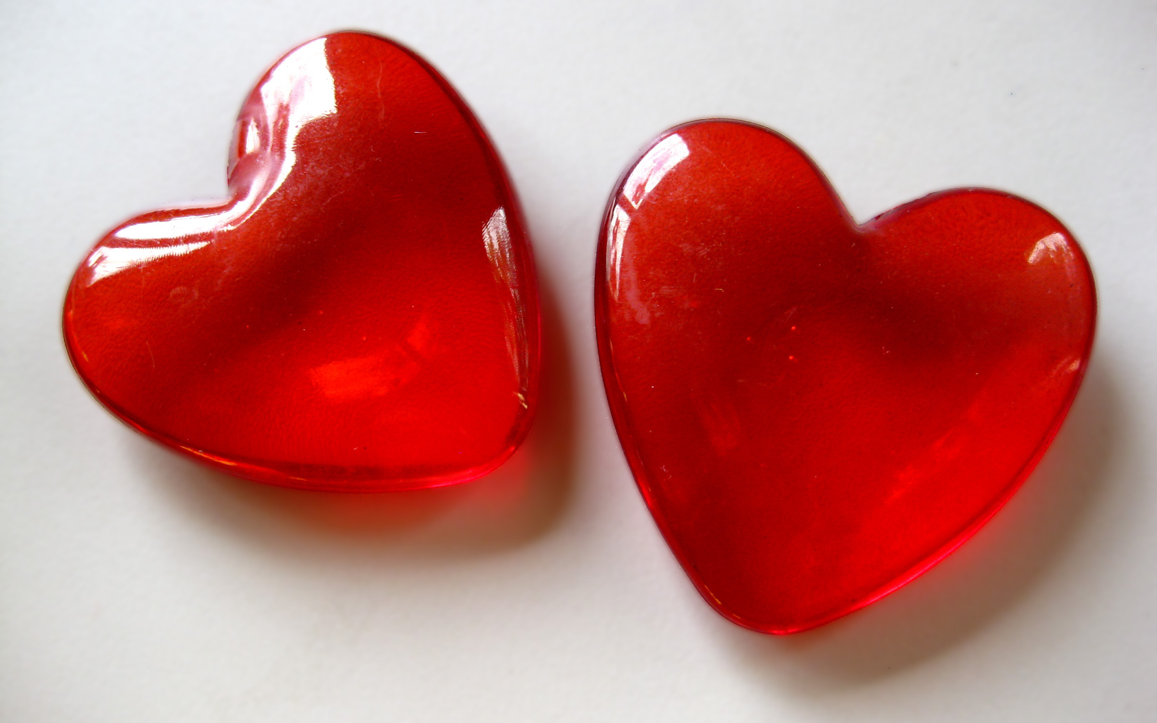 Два красных стеклянных сердца на сером фоне