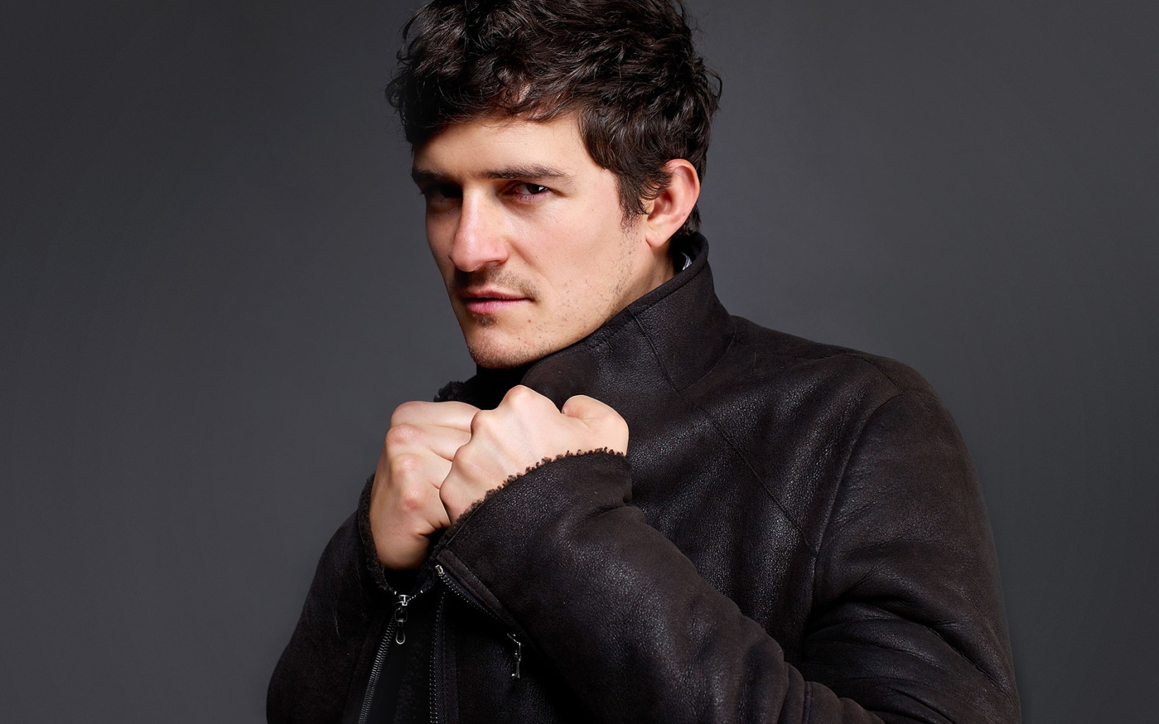 Красивый актер Орландо Блум на сером фоне