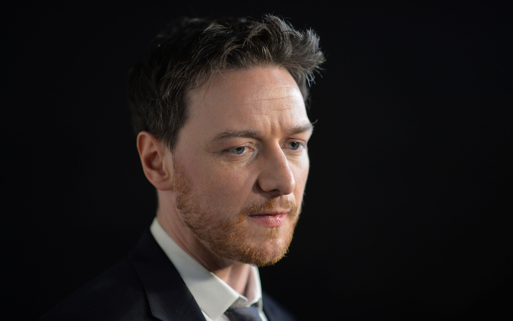 Грустный актер Джеймс МакЭвой на черном фоне