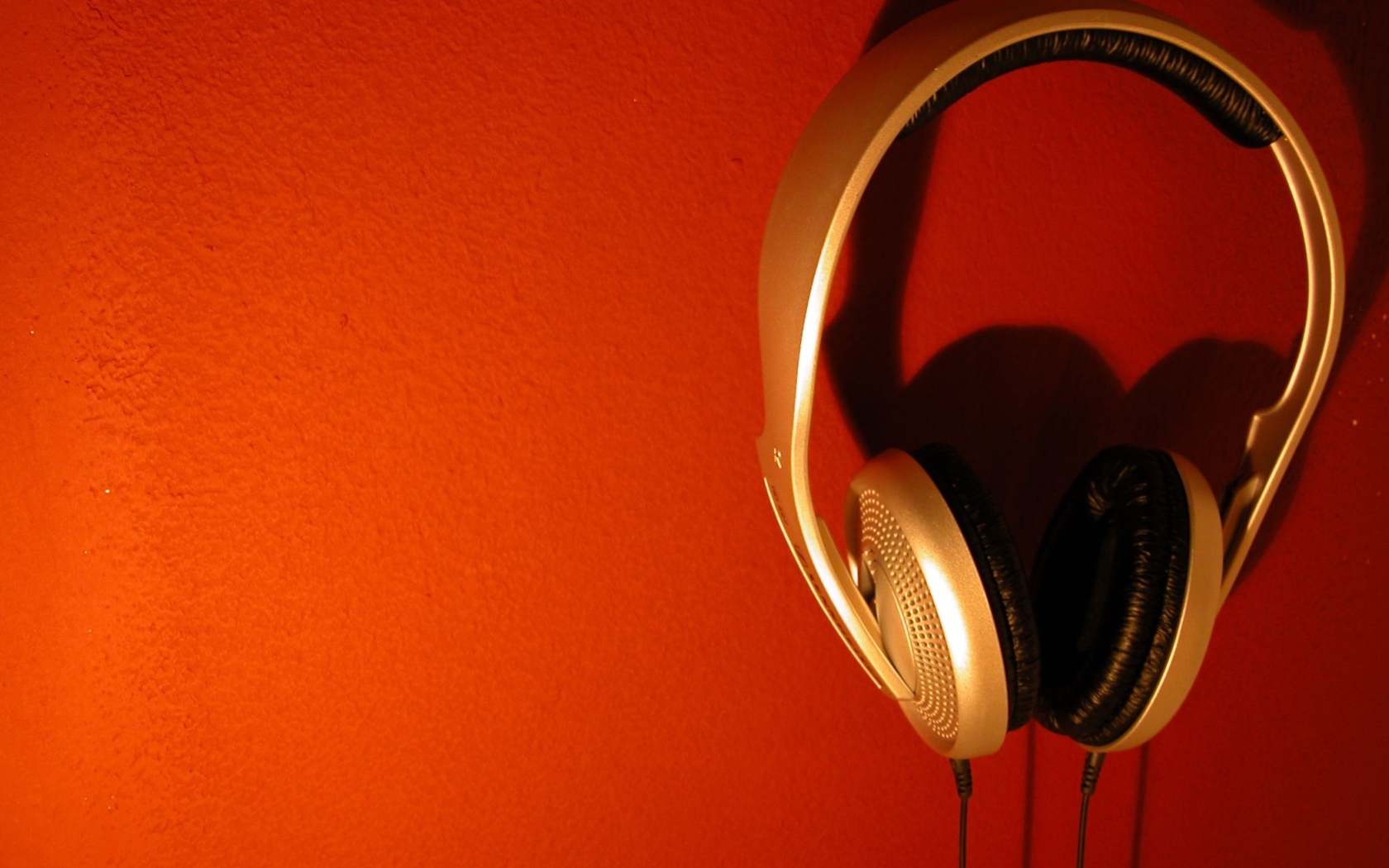 Большие золотые наушники на оранжевом фоне 
