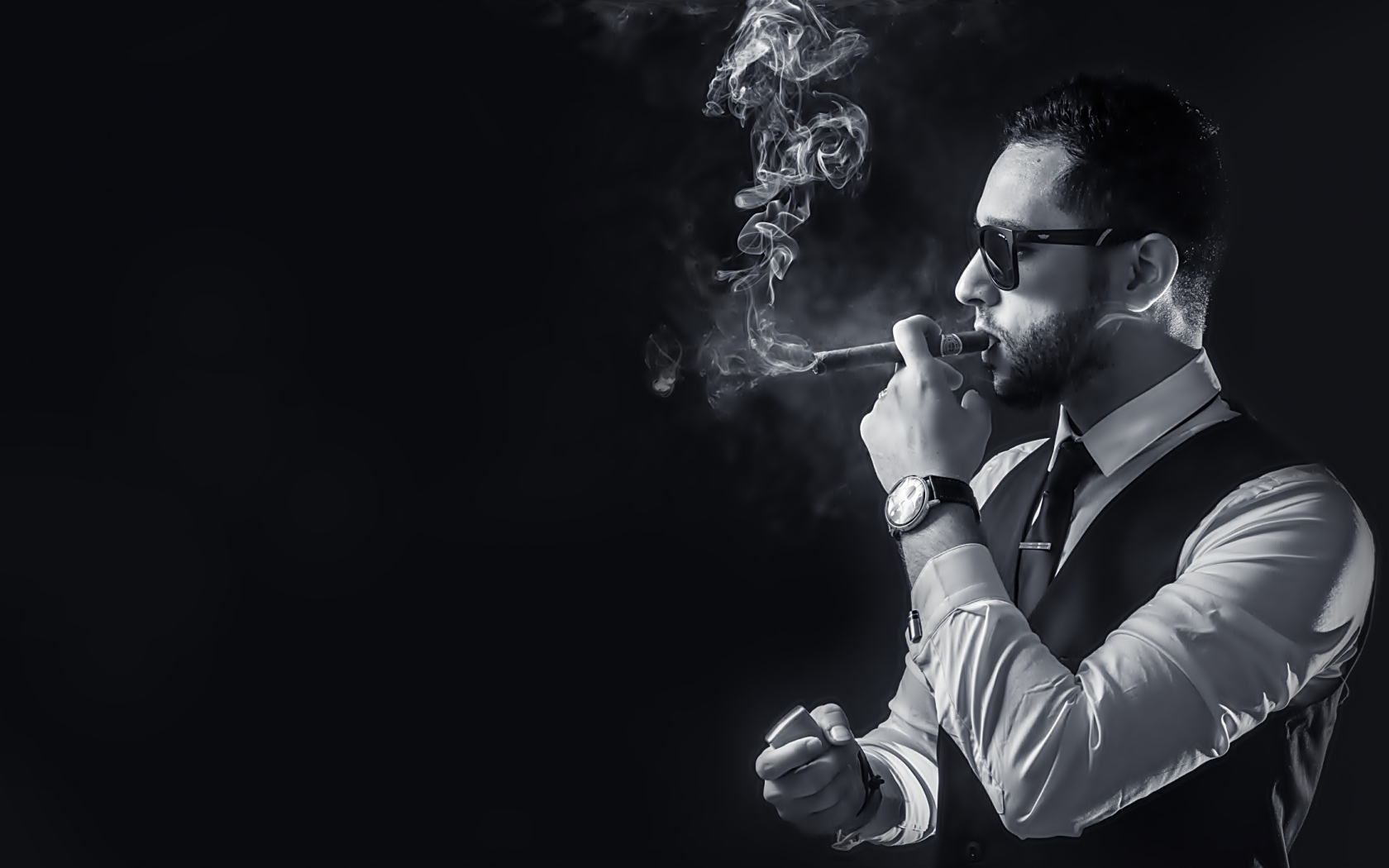 Мужчина с сигарой в руке на черном фоне 