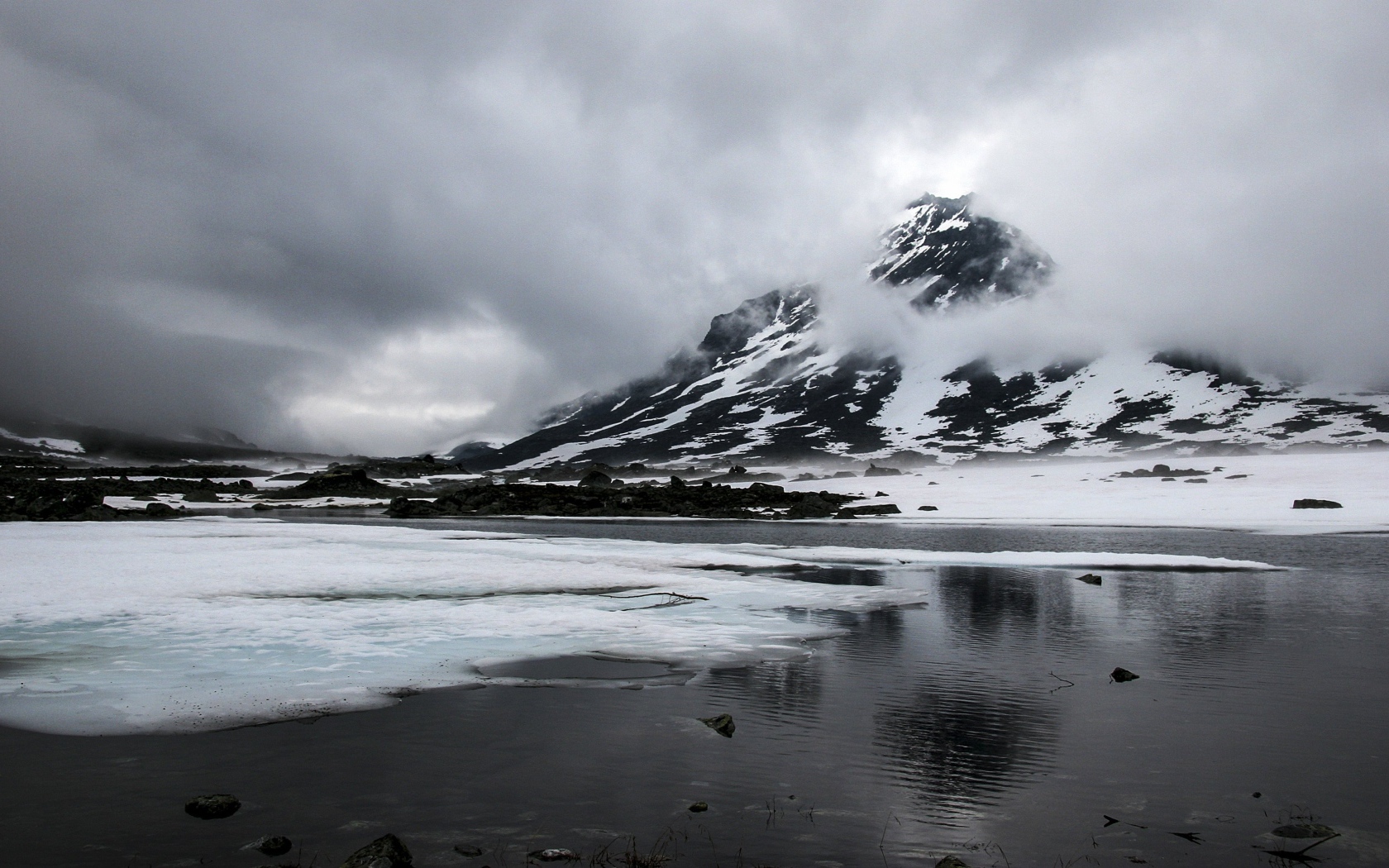 Cold gray fog over a snow-capped mountain by the lake