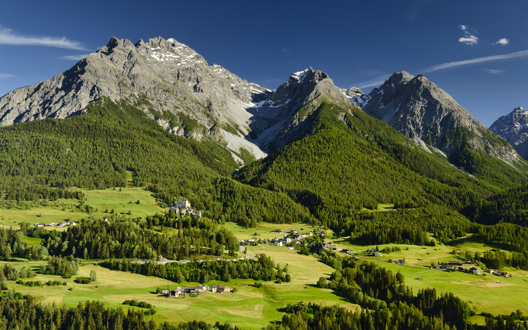 Высокие швейцарские Альпы покрыты зеленью под голубым небом 