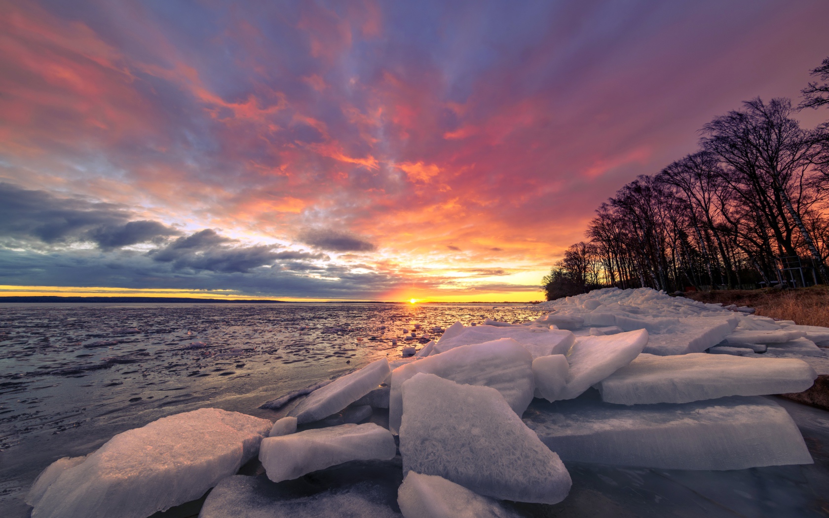 Глыбы льда лежат на берегу моря на закате