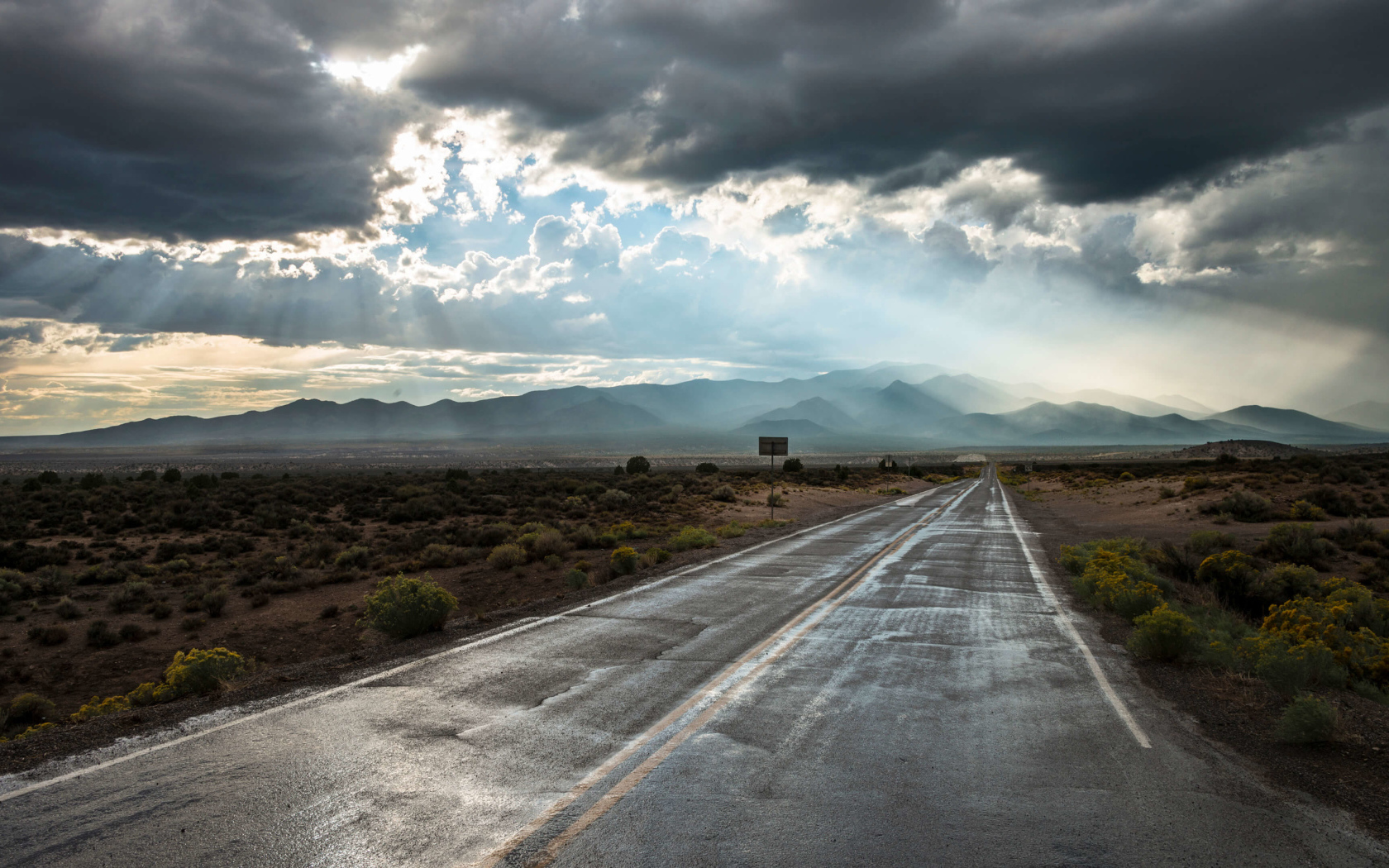 Мокрая дорога в лучах солнца под пасмурным небом 