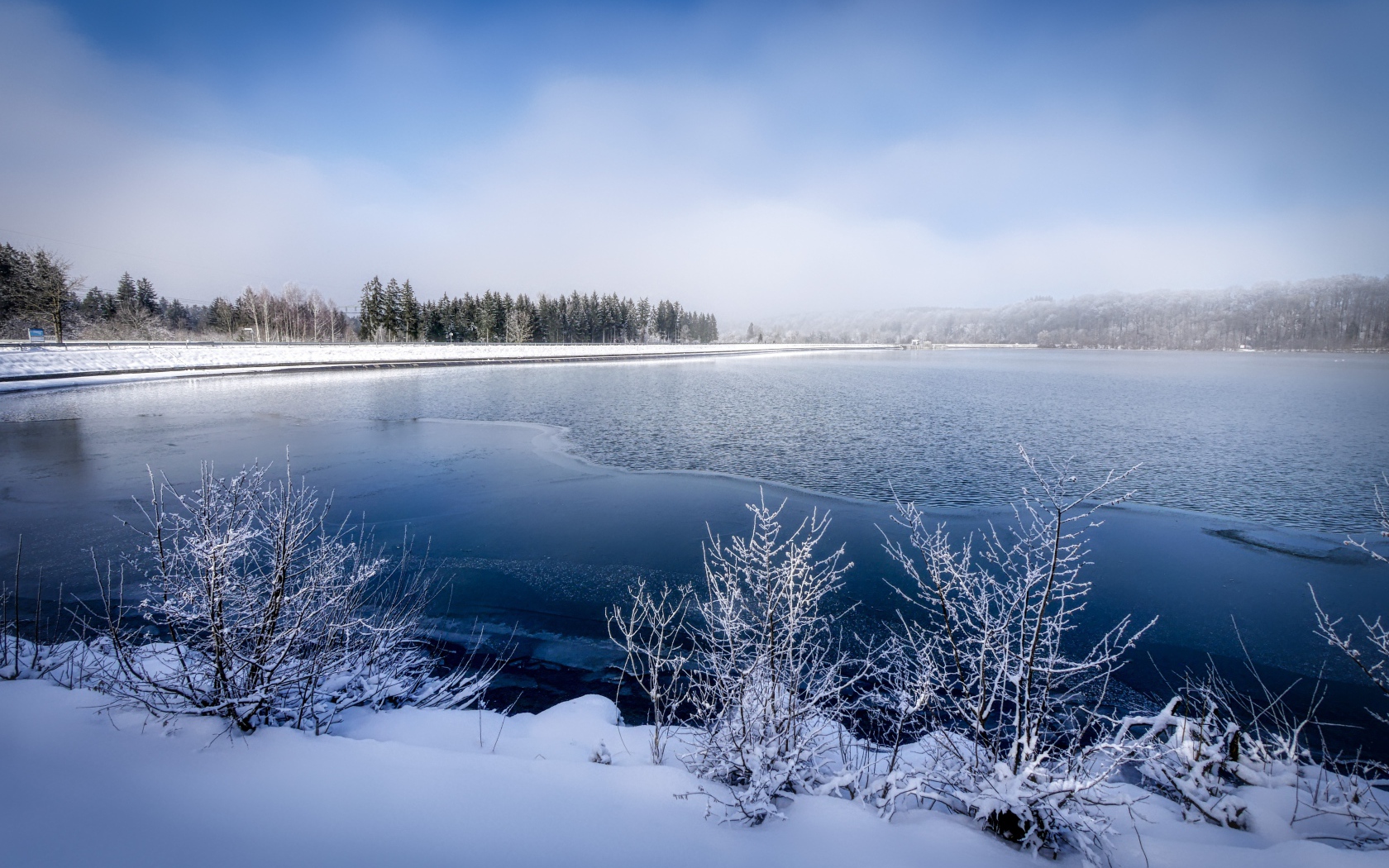 Покрытая льдом река  с заснеженными берегами зимой