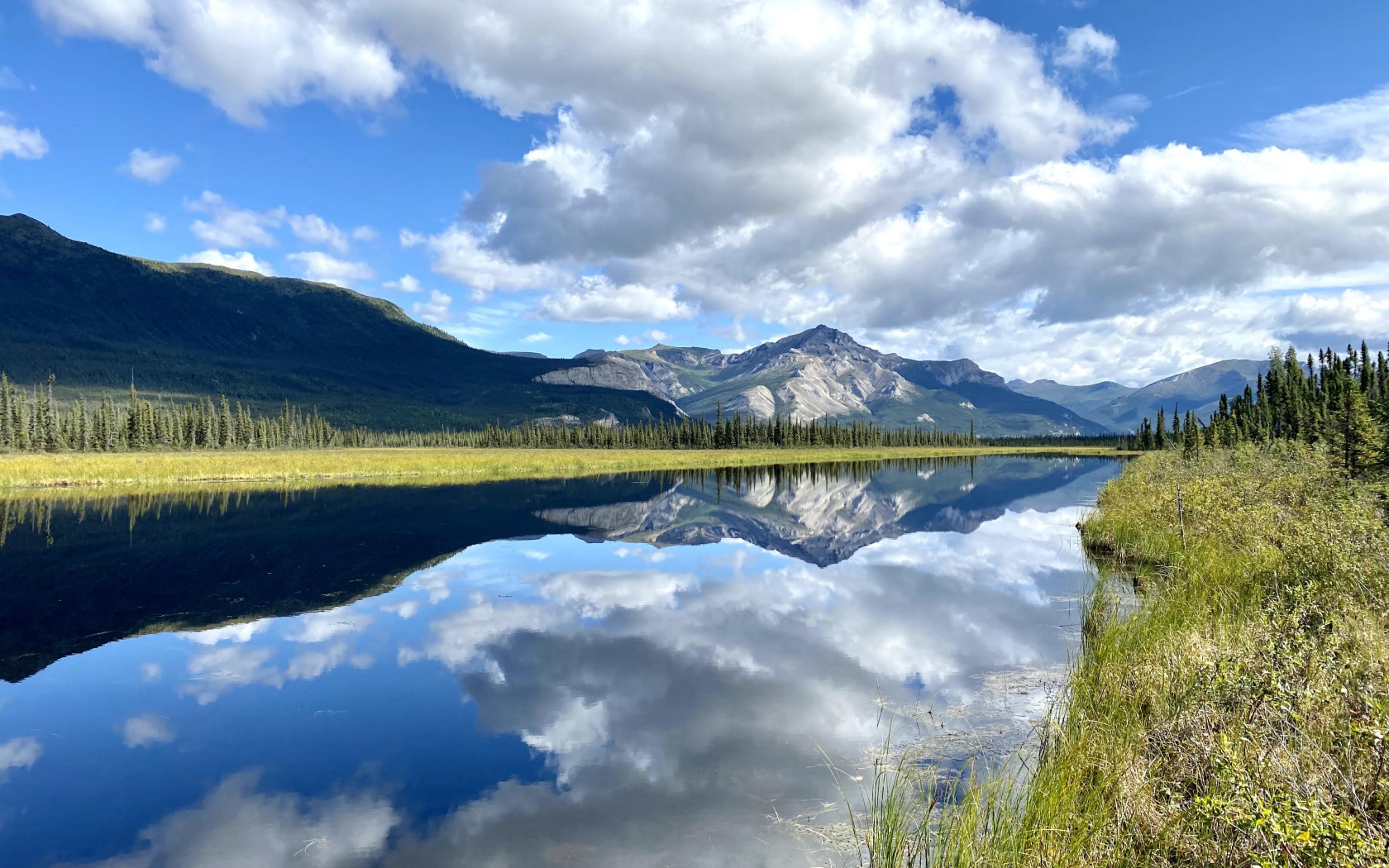 Небо с белыми облаками отражается в реке 