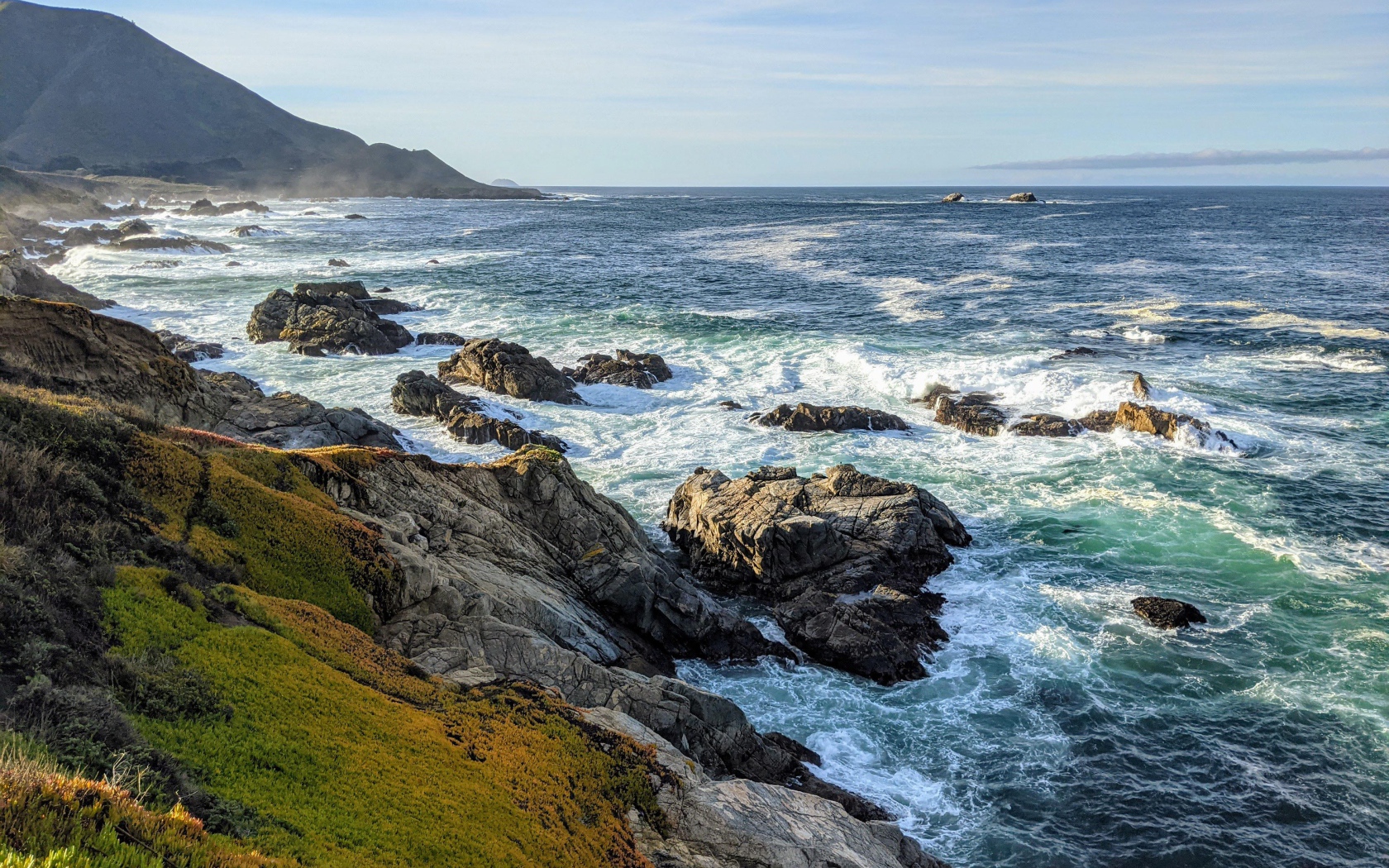 Голубая морская вода омывает камни на берегу 