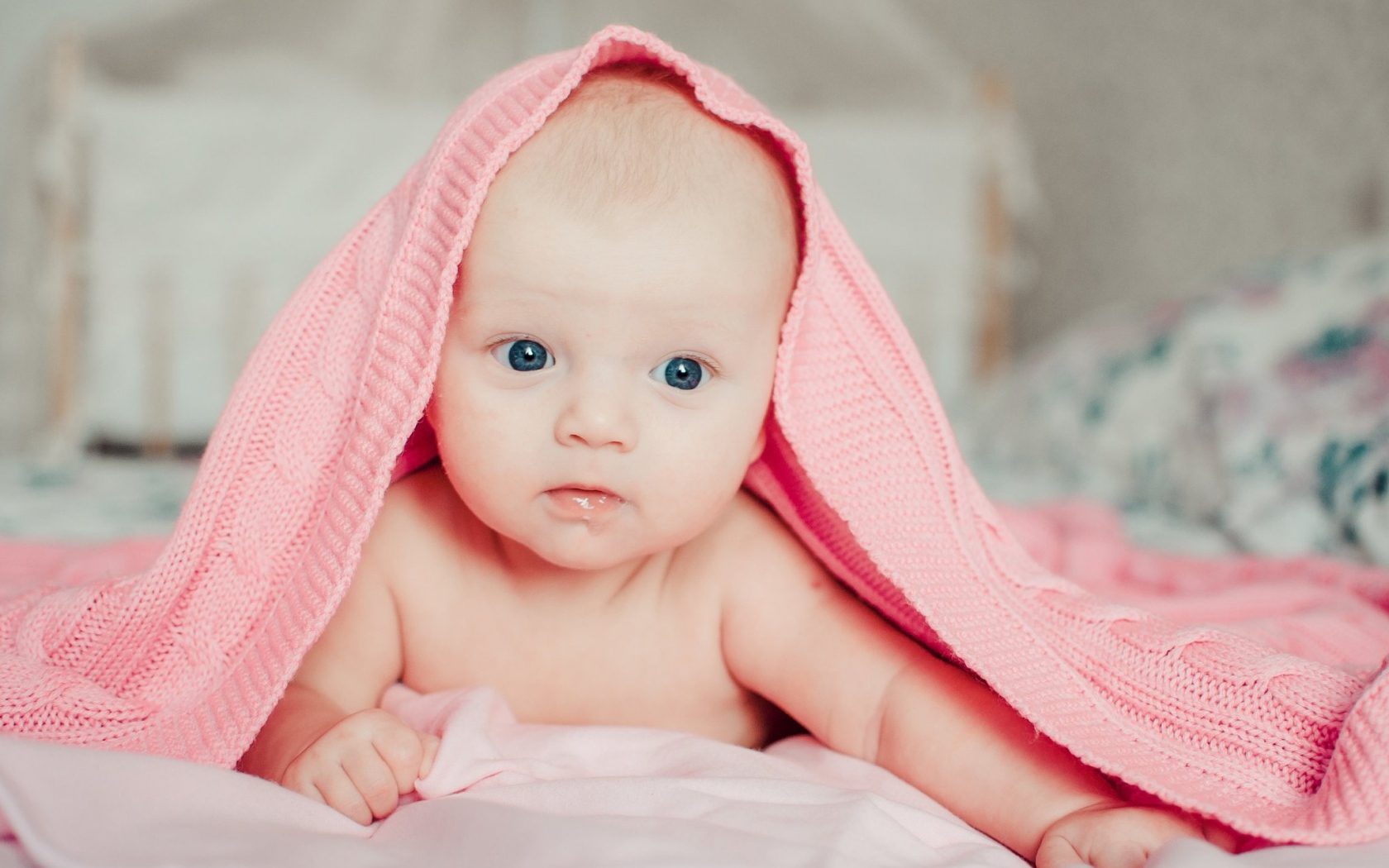 Грудной ребенок лежит под розовым пледом