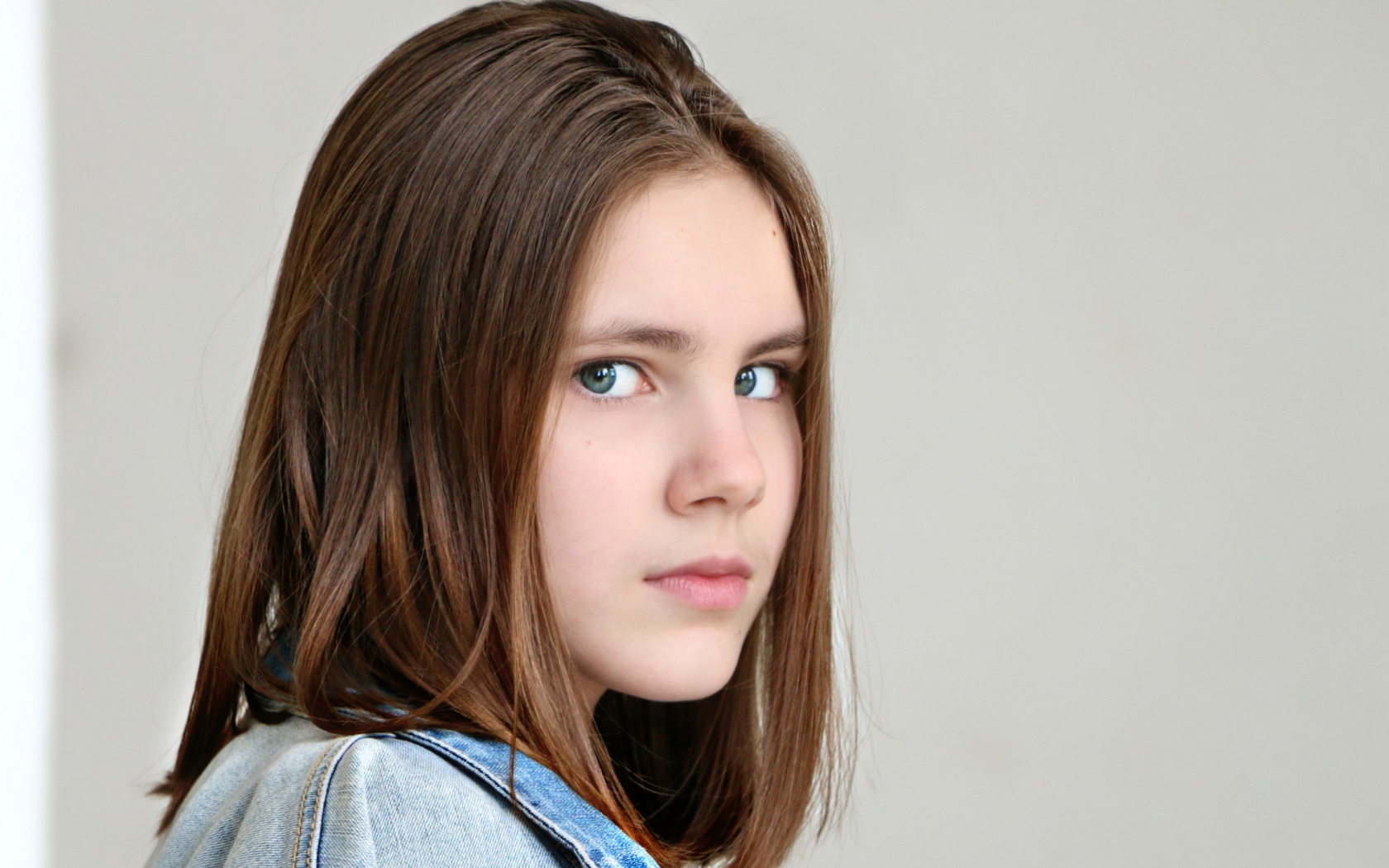 Красивая зеленоглазая девочка на сером фоне