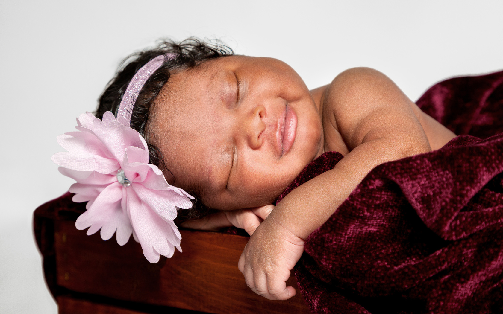 Темнокожая маленькая девочка с розовым цветком на голове 