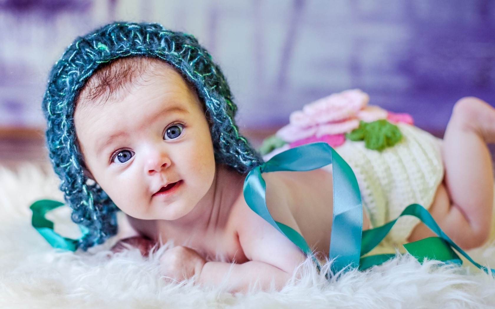 Голубоглазая маленькая девочка в вязаной шапке с ленточками