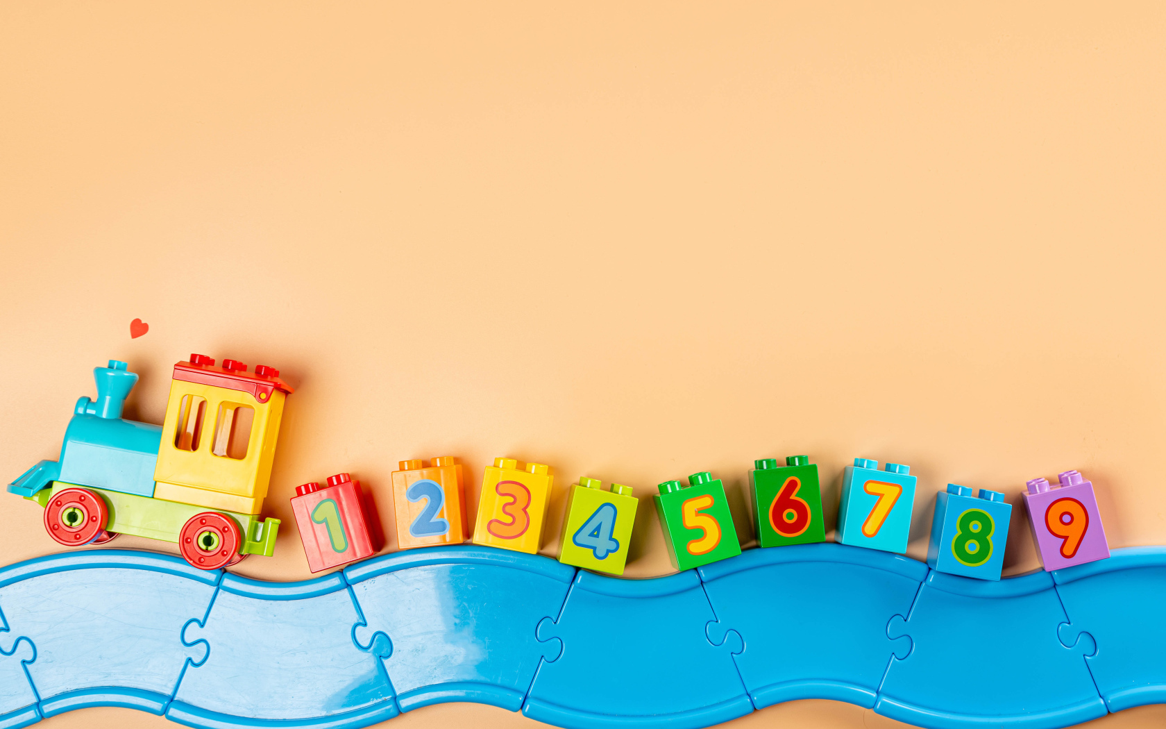 Детский игрушечный паровоз на бежевом фоне 