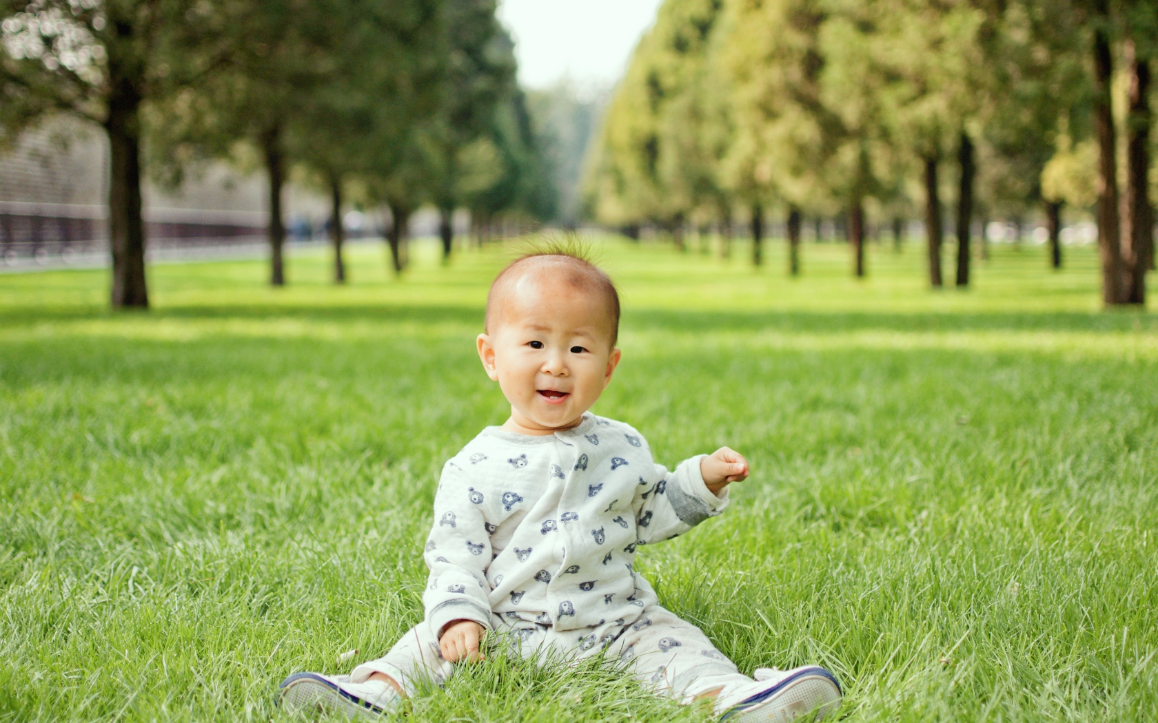 Маленький ребенок азиат сидит на зеленой траве 