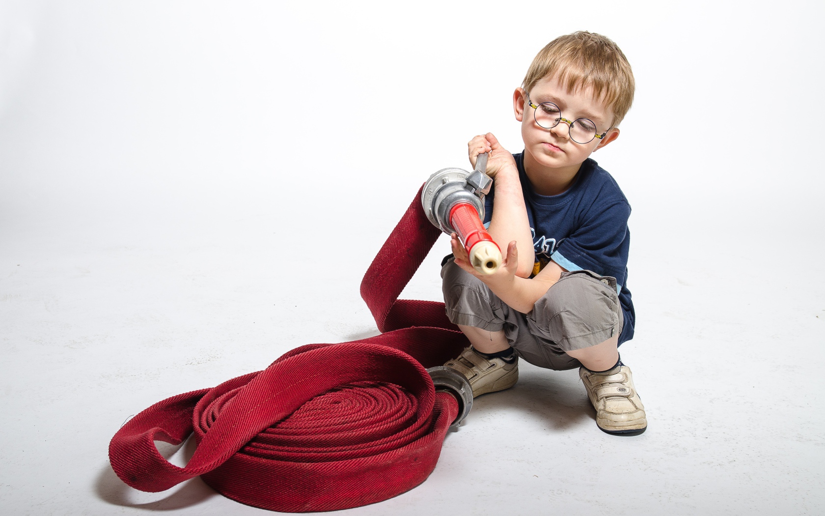 Маленький мальчик на белом фоне играет в пожарного