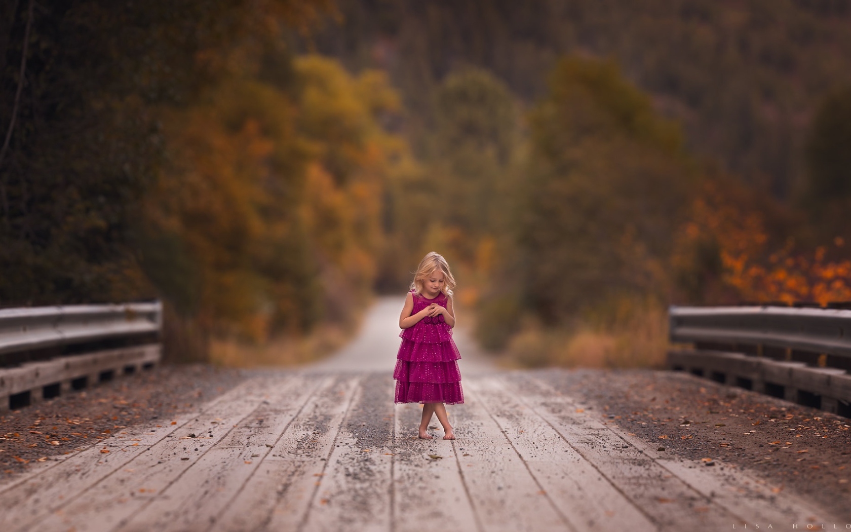Маленькая девочка в платье стоит на мосту 