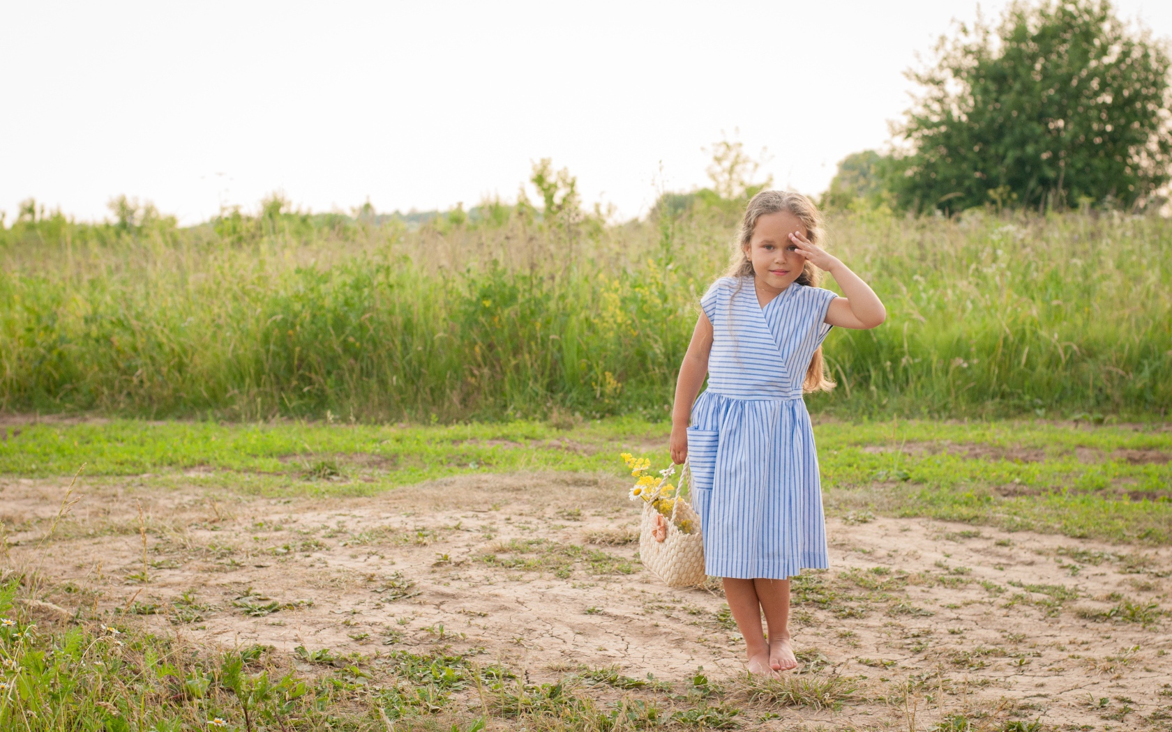 Маленькая девочка с сумкой на поле с травой 