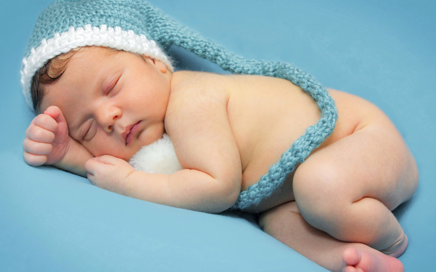 Маленький спящий ребенок в шапке на голубом фоне 