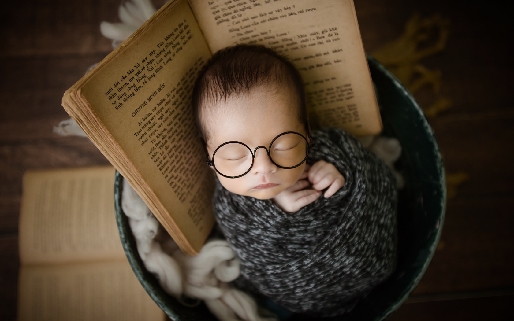 Маленький спящий ребенок в ведре с книгой 