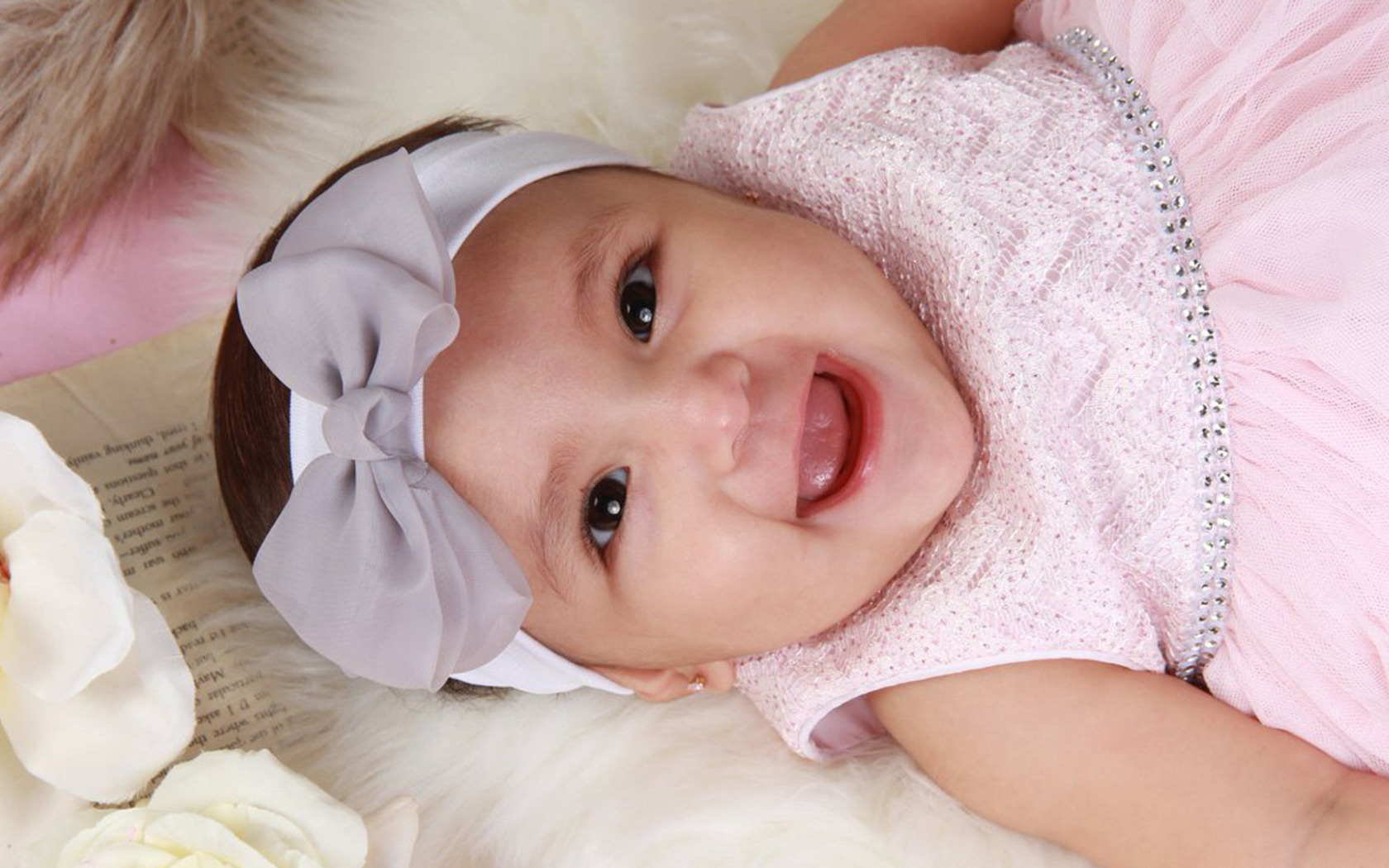 Улыбающаяся девочка в розовом платье с бантом на голове