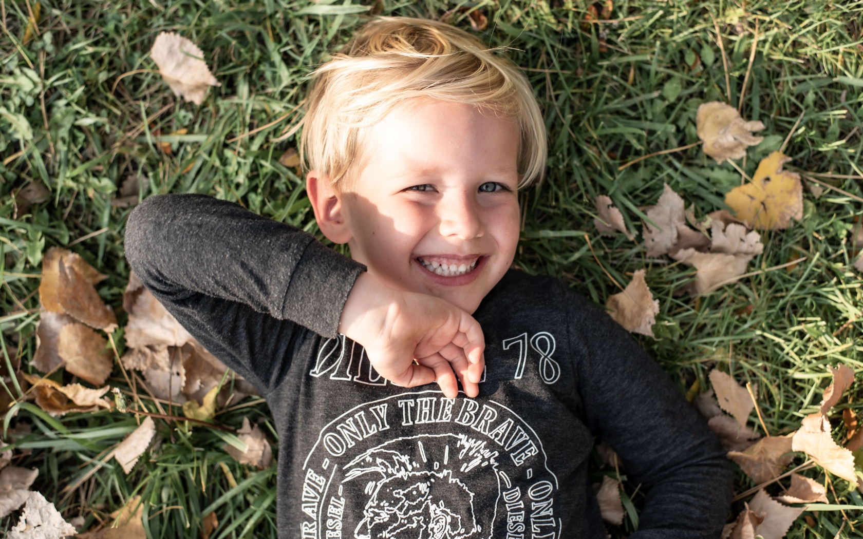 Улыбающийся маленький мальчик лежит на траве