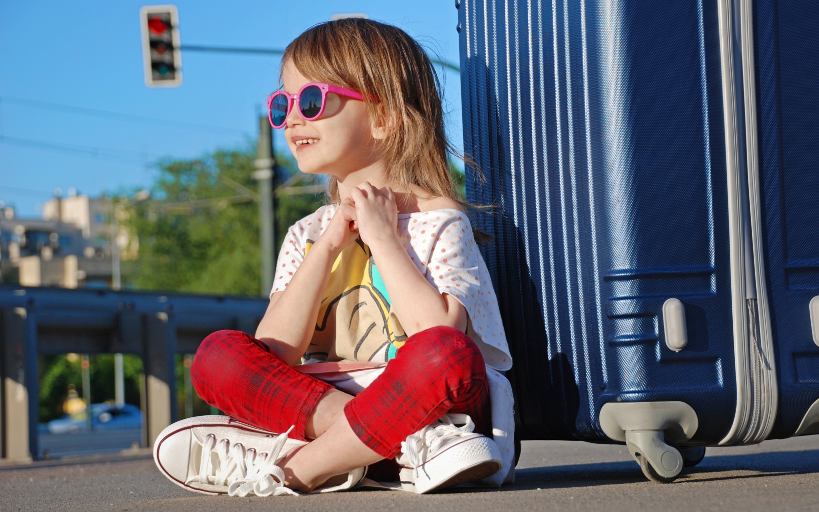 Улыбающаяся маленькая девочка в очках с чемоданом