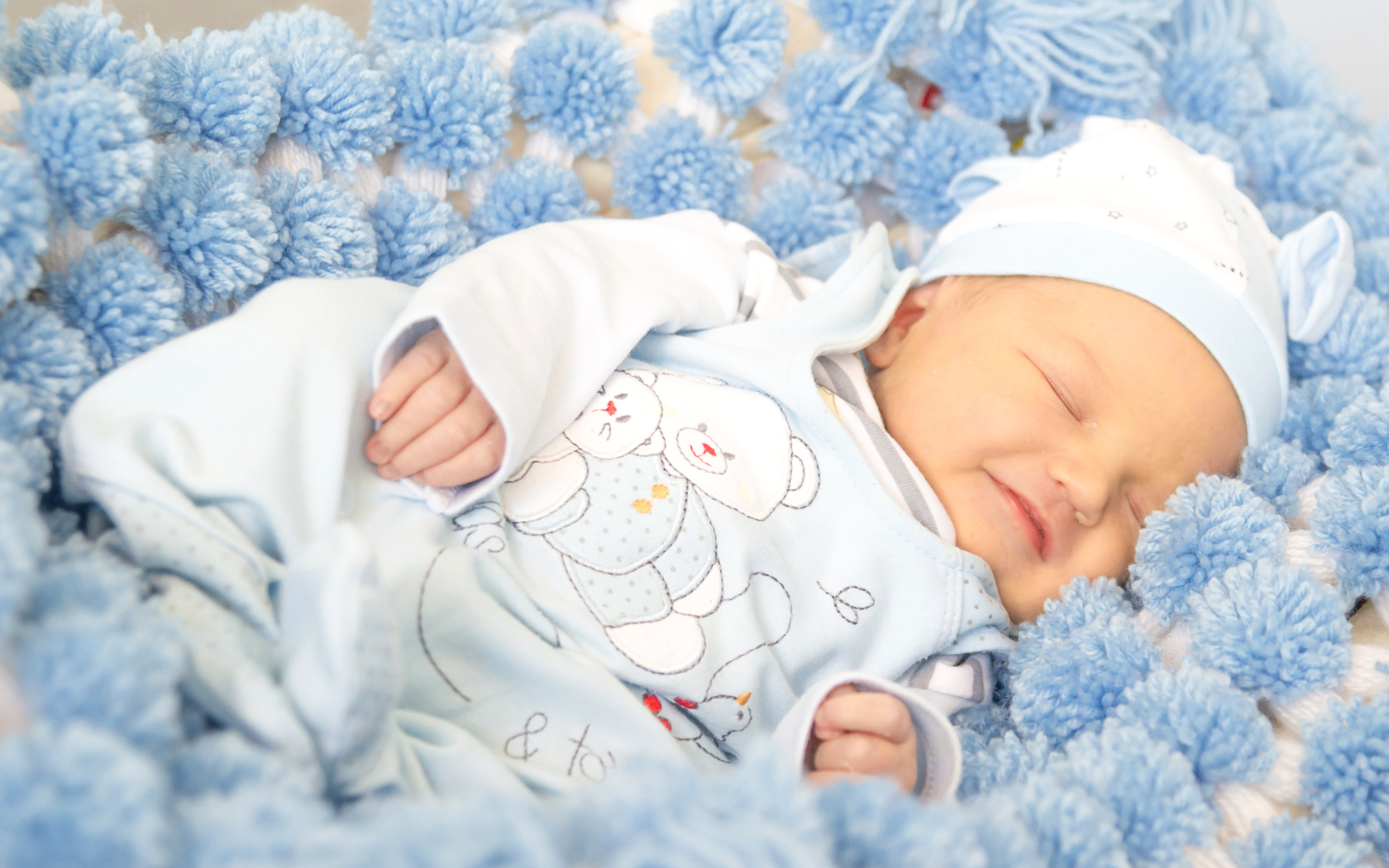 Улыбающийся грудной ребенок спит на голубом покрывале