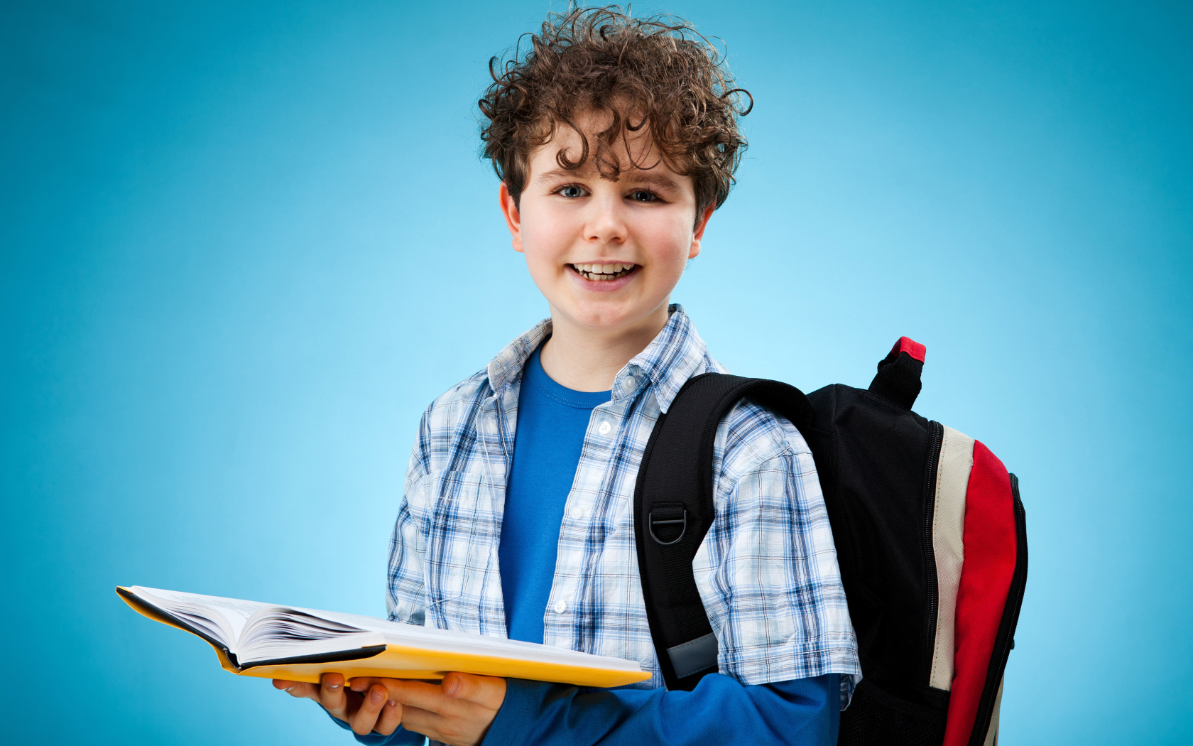 Улыбающийся мальчик школьник с книгой в руках 