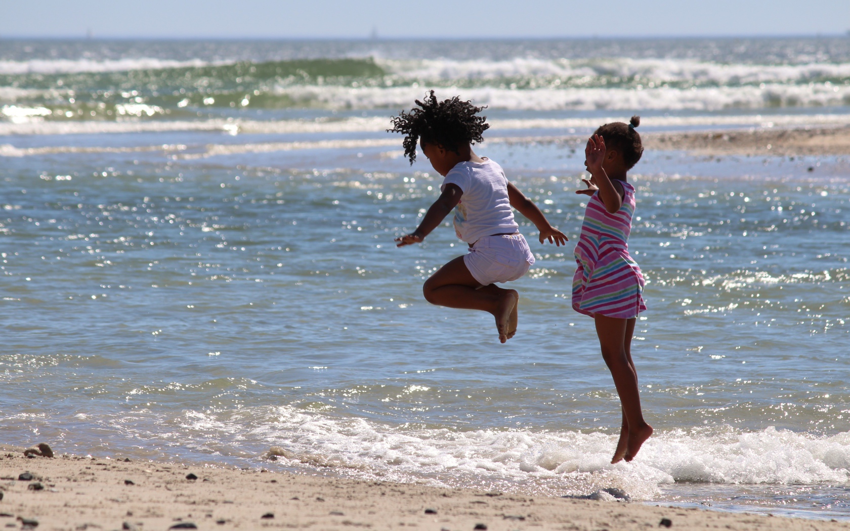 Две маленькие девочки играют на морском берегу