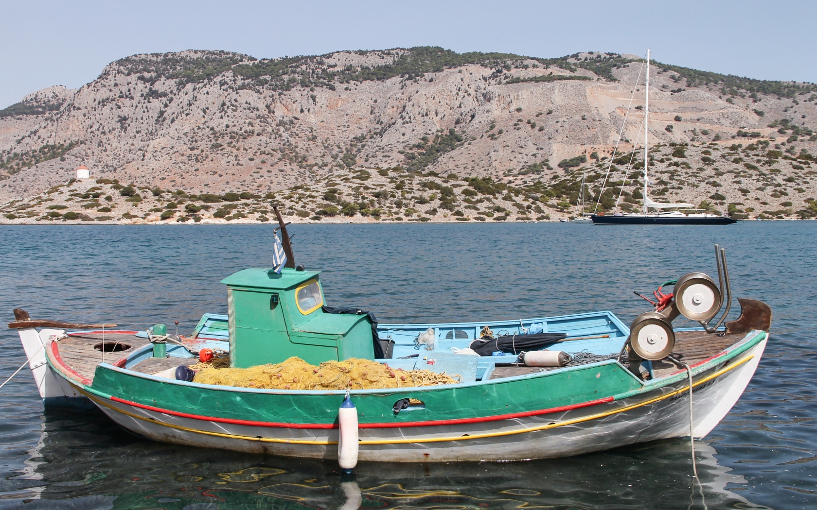 Рыбацкая лодка в воде на фоне горы
