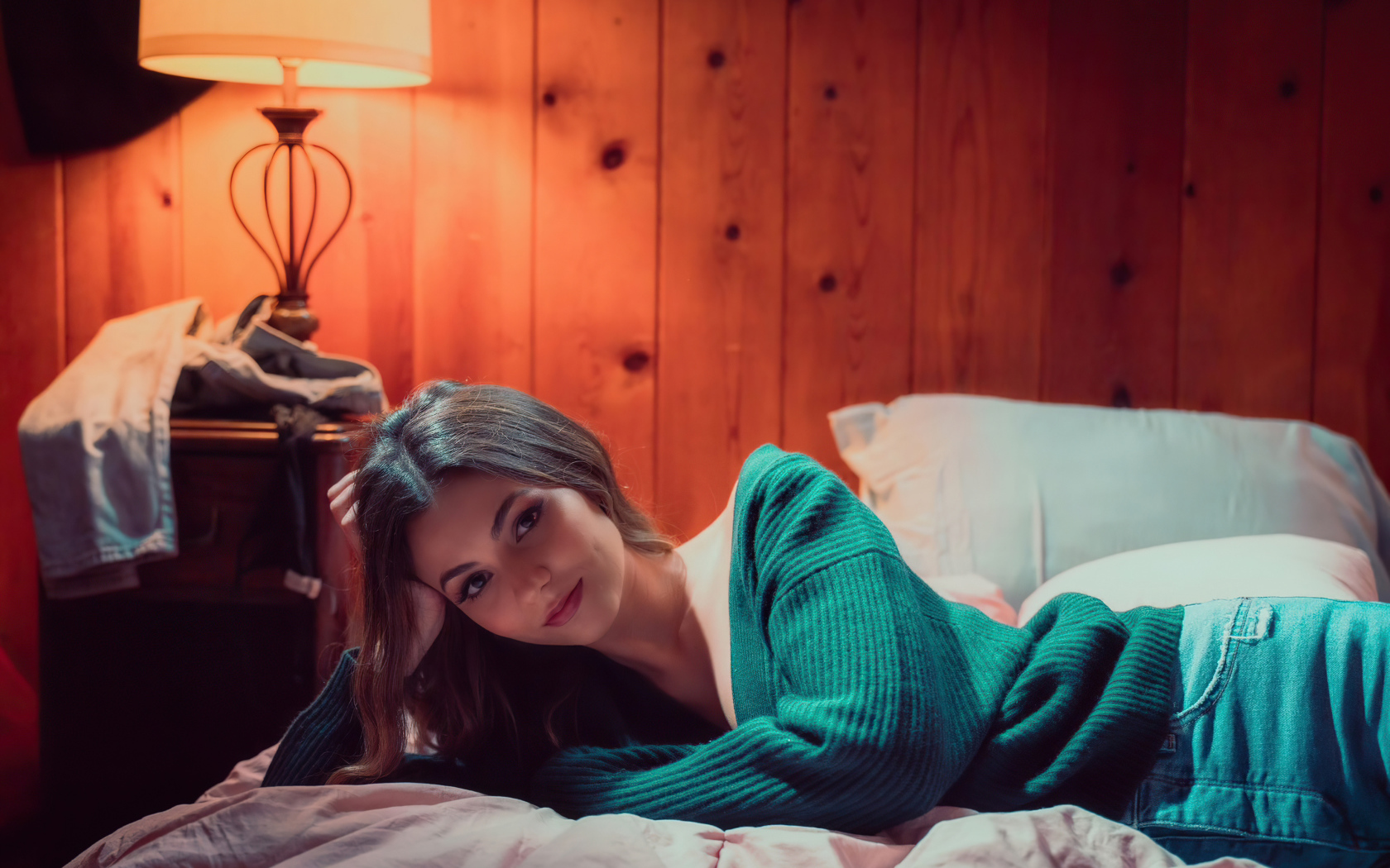 Актриса  Виктория Джастис в зеленом свитере на кровати