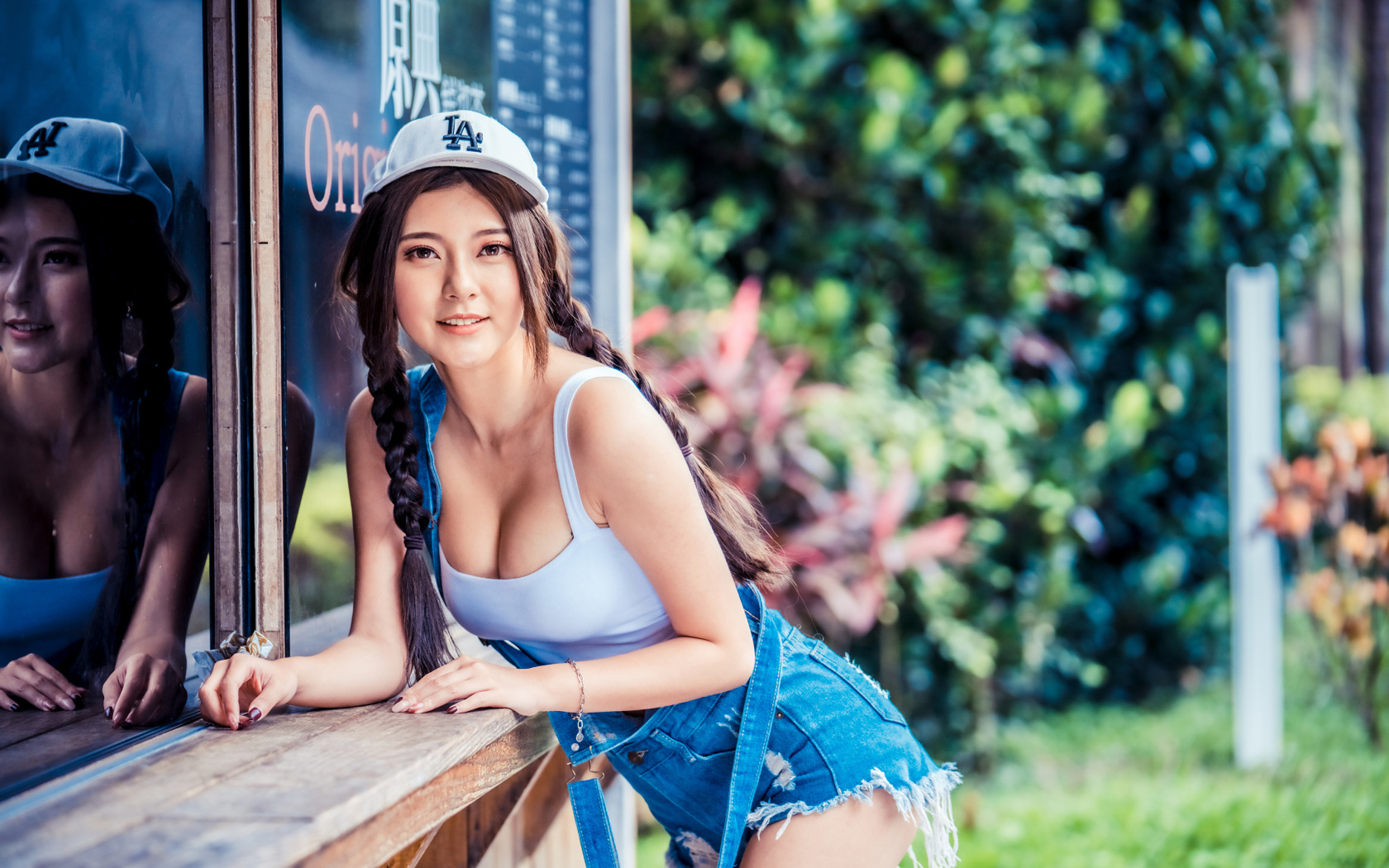 Спортивная девушка азиатка в кепке стоит у магазина