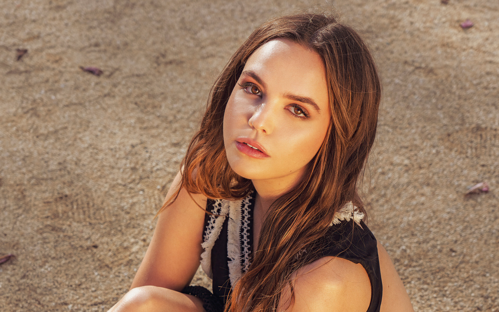 Кареглазая актриса Бэйли Мэдисон сидит на песке