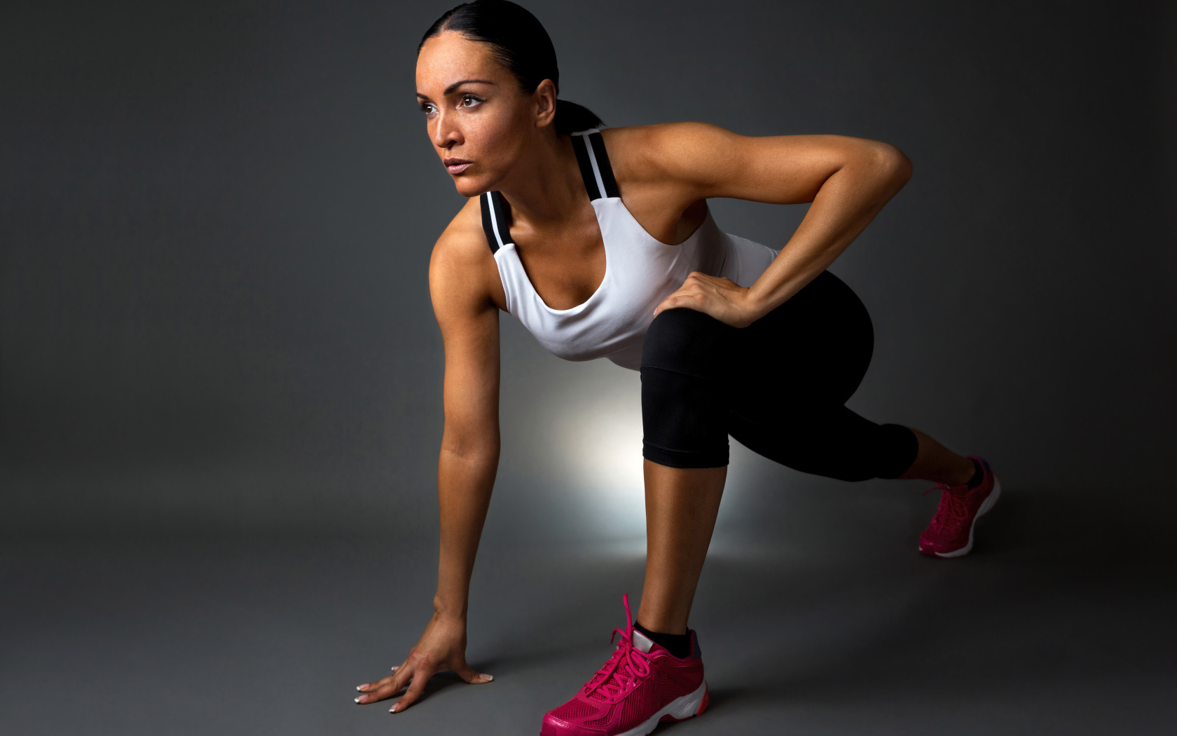 Девушка спортсменка в стойке на сером фоне 