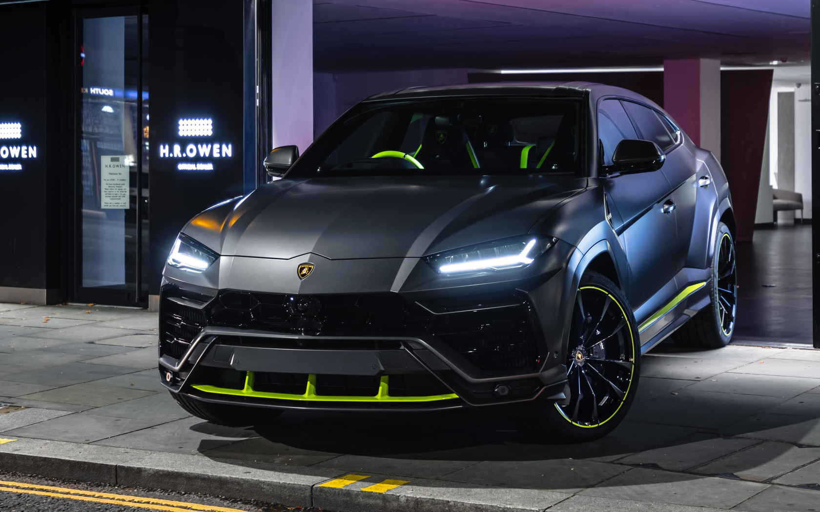 Серебристый Lamborghini Urus с включенными фарами