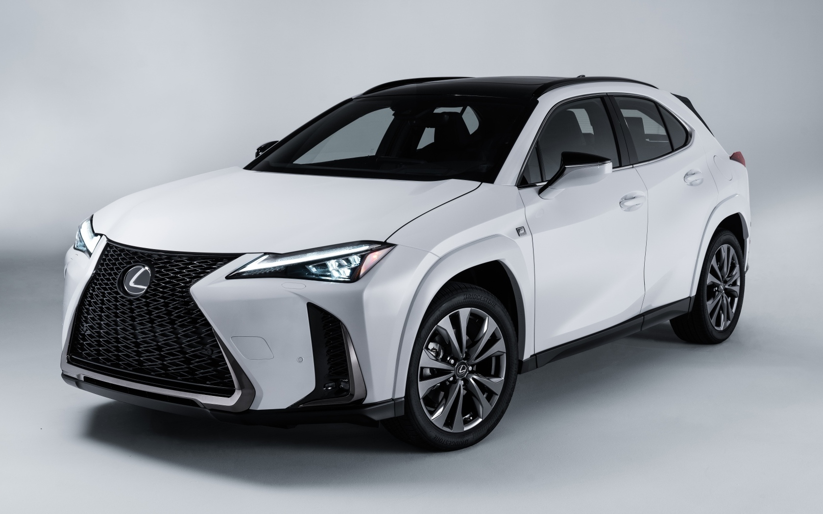 Белый автомобиль Lexus UX 250h AWD F SPORT, 2023 года на сером фоне