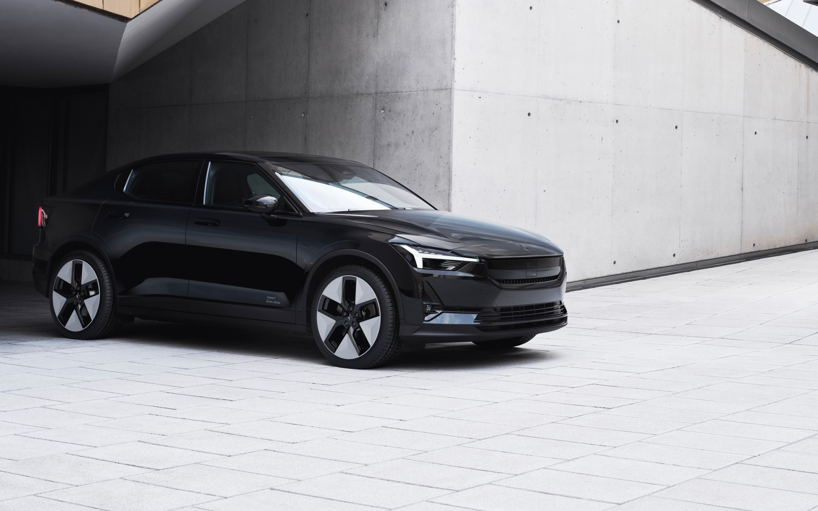 Черный автомобиль Polestar 2 2023 года у серой стены