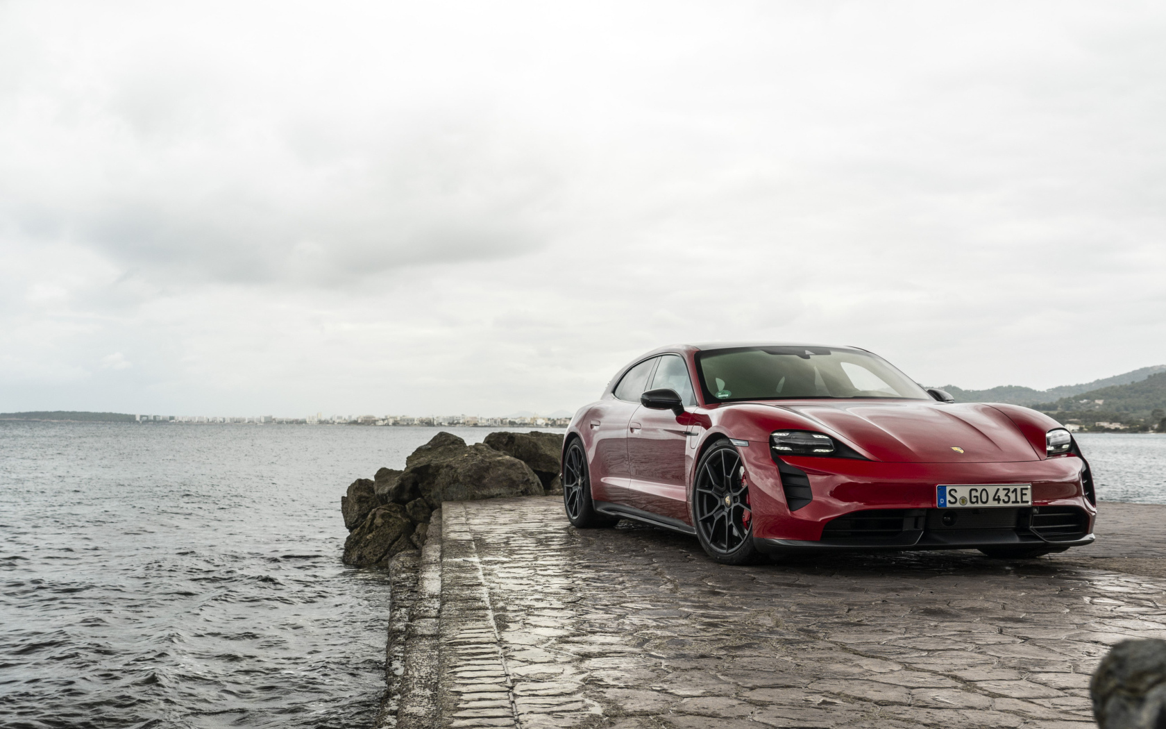 Красный автомобиль Porsche Taycan  у воды