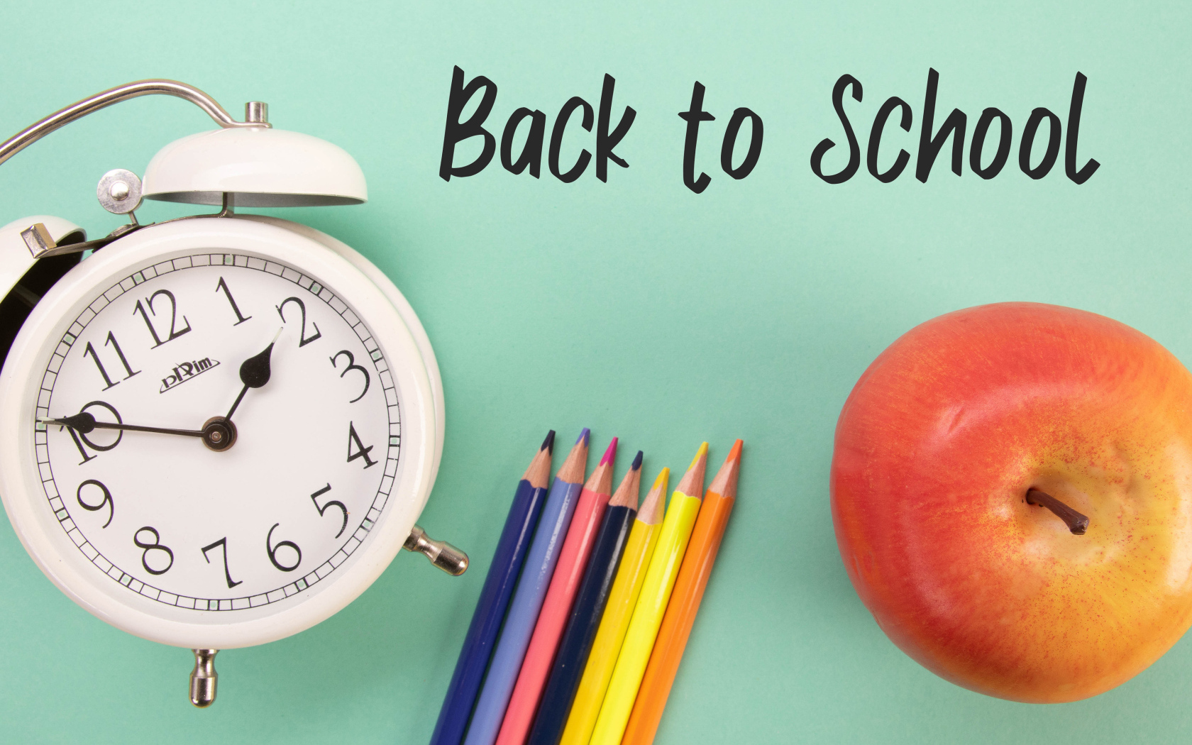 Цветные карандаши на голубом фоне с часами и яблоком