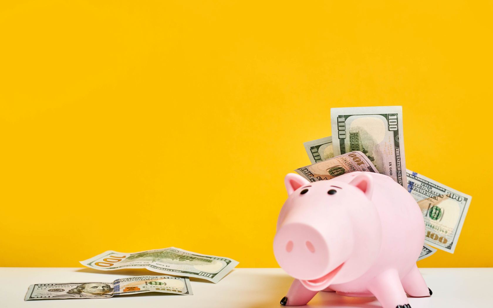 Pink pig piggy bank with banknotes on a yellow background