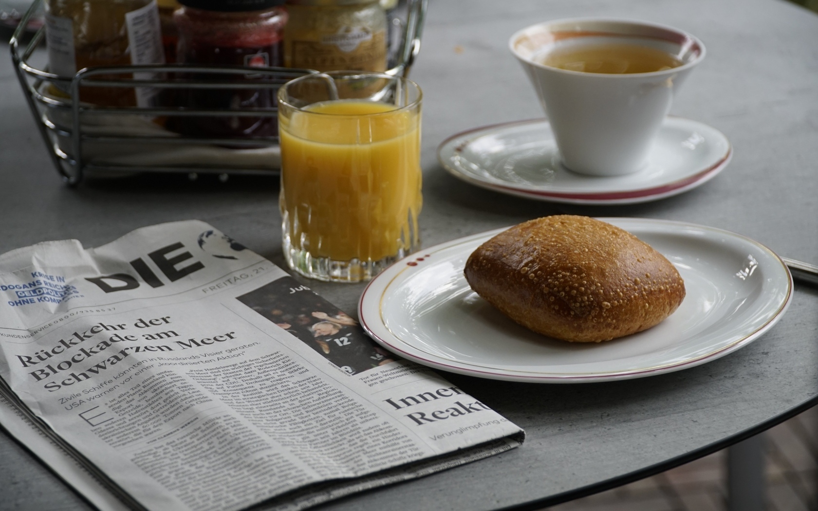 Булочка и стакан сока на столе с газетой