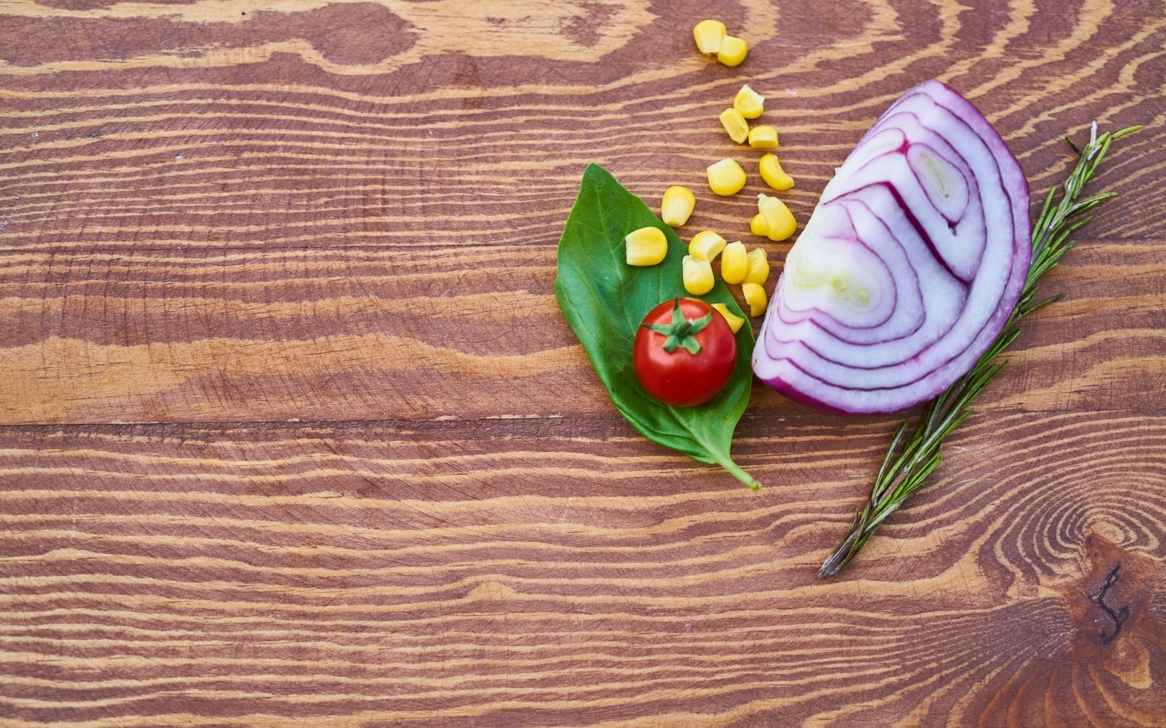 Половина лука на столе с кукурузой и помидором