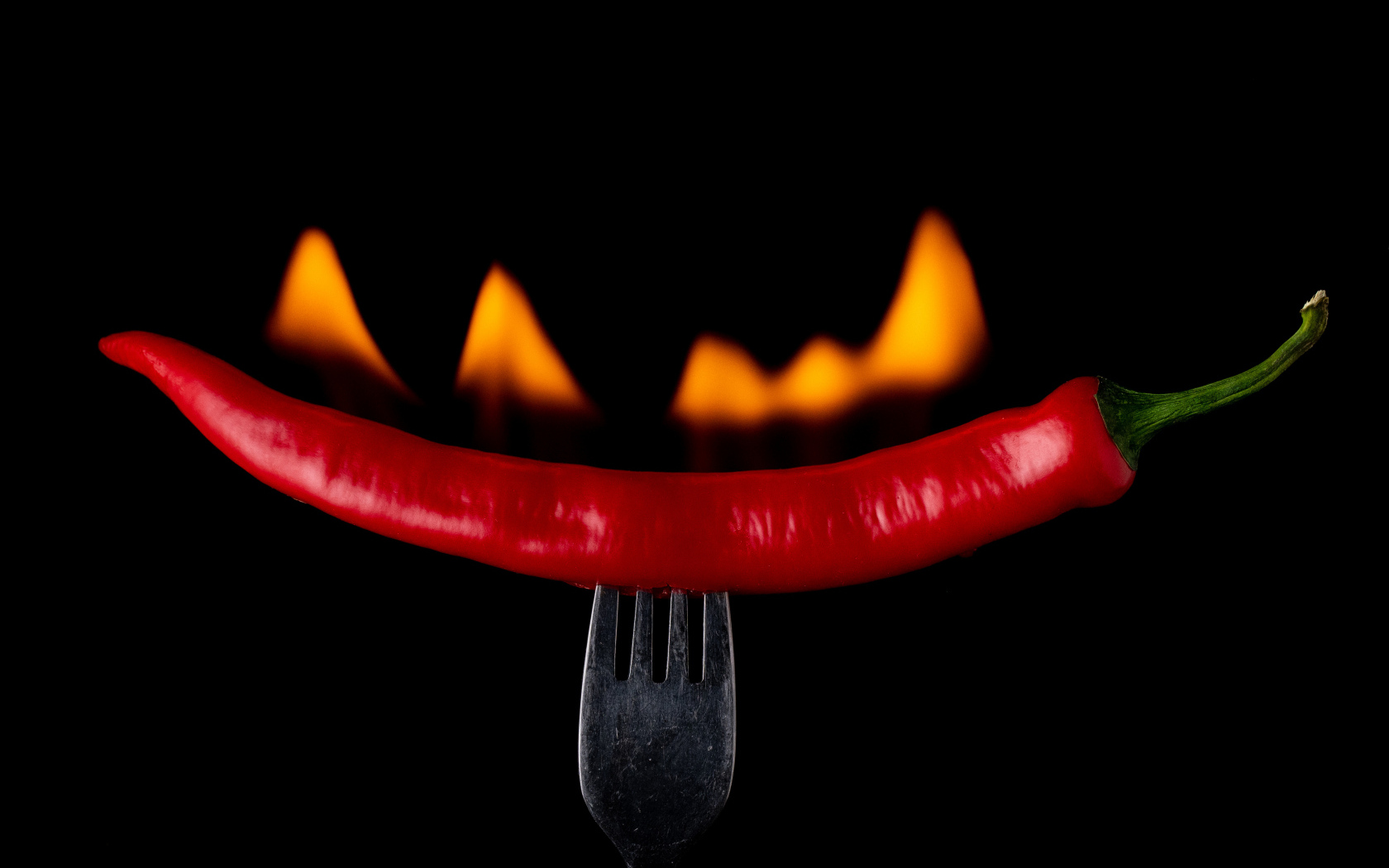 Жгучий красный перец на вилке на черном фоне