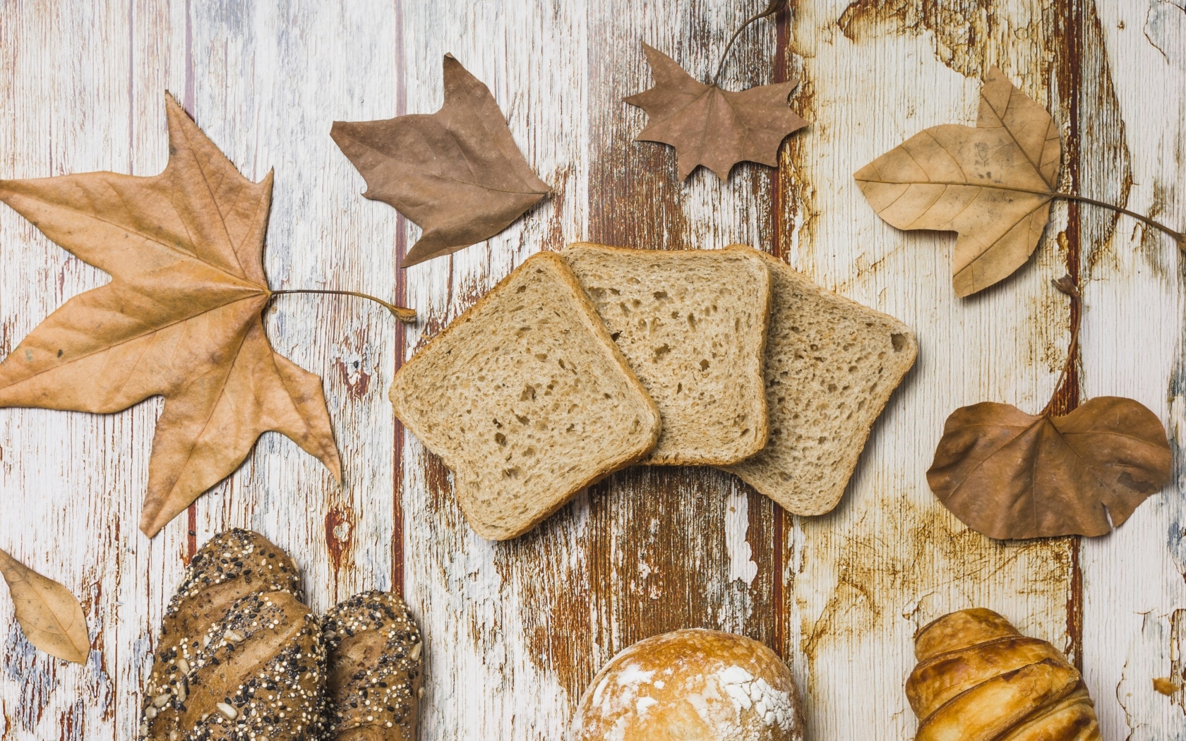 Куски хлеба с листьями на деревянном столе